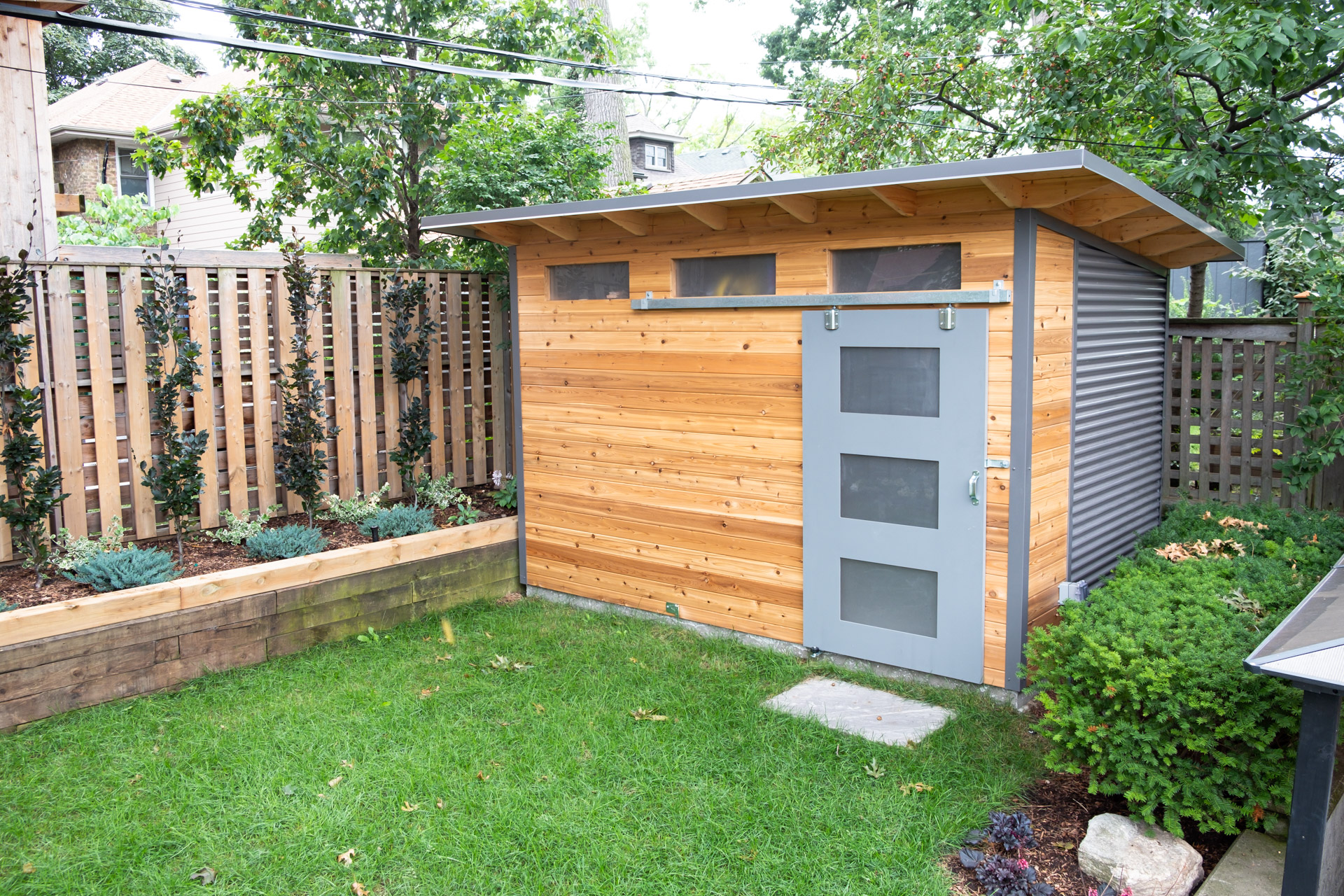 12x8 Advanced Shed with Western Red Cedar front wall, charcoal corrugated steel siding, and Kendall Charcoal sliding barn door with frosted glass panels in Toronto Ontario, installed by Backyard Escape Studios.