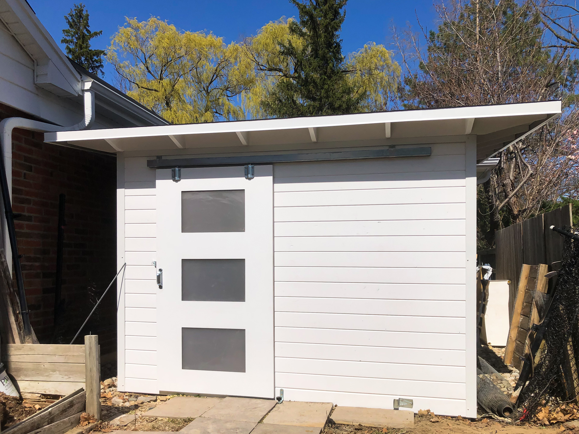 10x8 Advanced Storage Shed with White Satin horizontal pine T+G siding and 42" sliding barn door with frosted lexan glass panels in London Ontario, installed by Backyard Escape Studios.