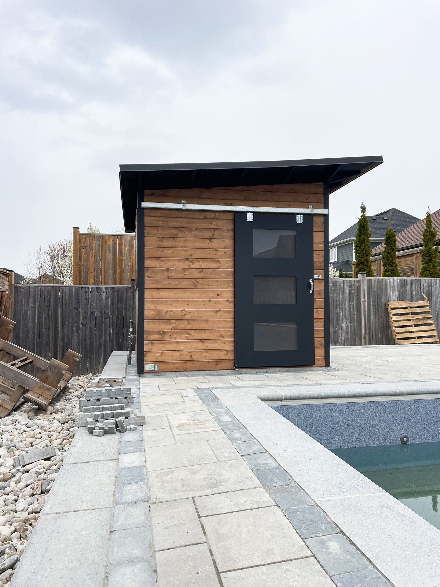 Front view of 10x8 Advanced Shed in Strathroy Ontario showing 42-inch sliding barn door with frosted Lexan glass panels and cedar tongue-and-groove siding stained Muskoka Brown, installed by Backyard Escape Studios.