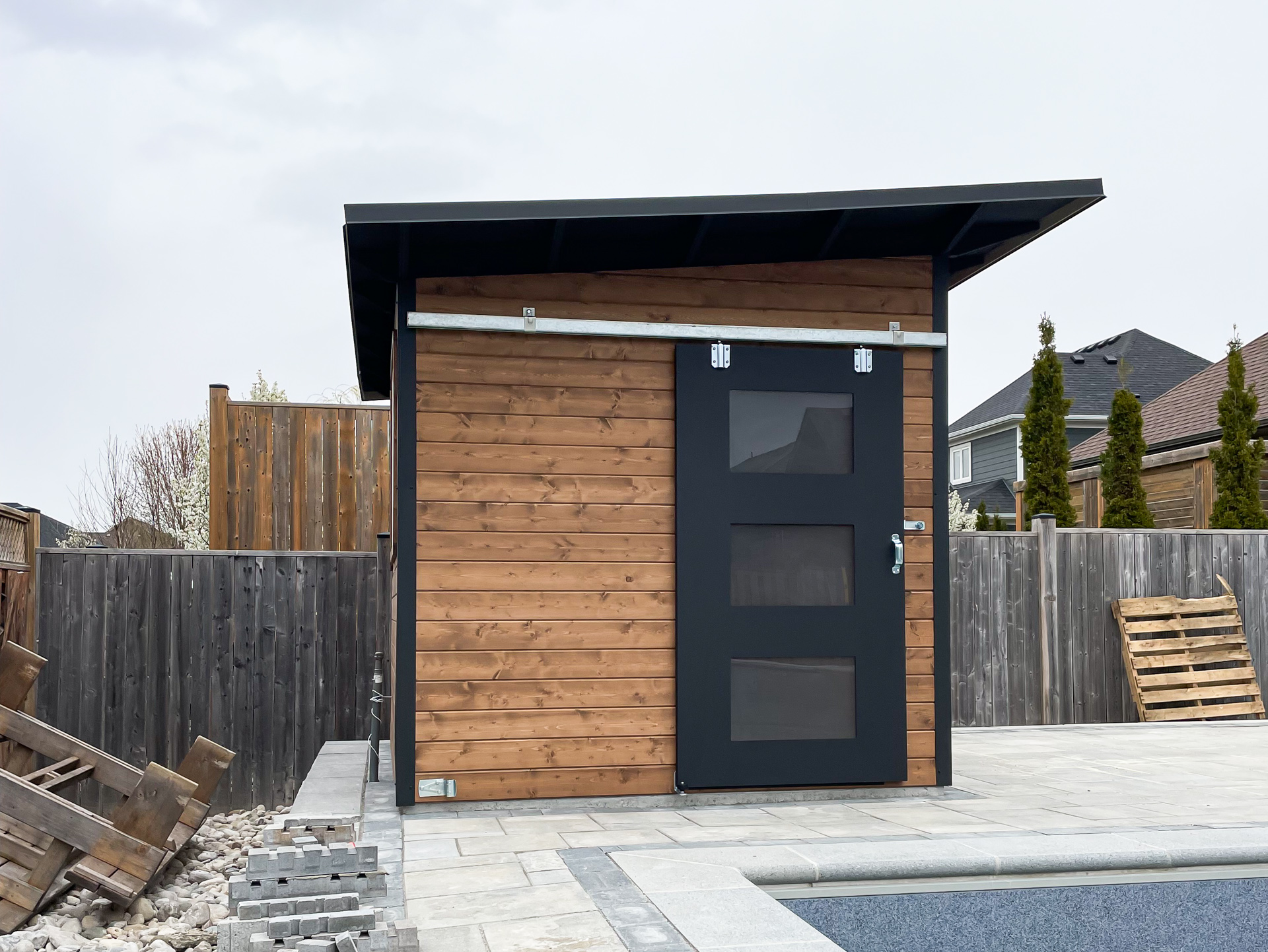 10x8 Advanced Shed with cedar T+G siding in Muskoka Brown and Black Beauty sliding barn door, front angle view, Strathroy Ontario, installed by Backyard Escape Studios.