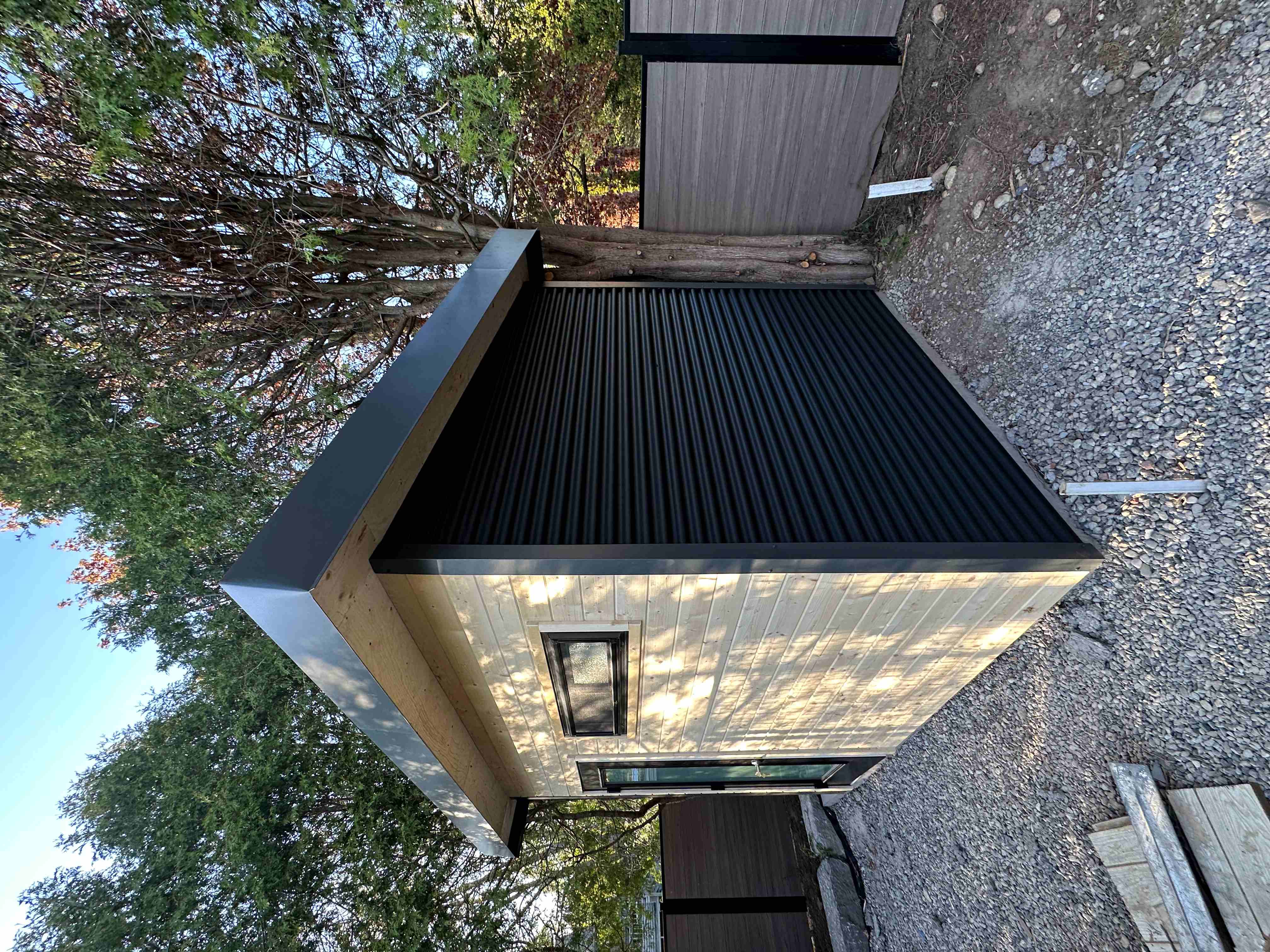 10x7.5 Suburban Shed with natural pine front wall, Iron Ore corrugated steel siding, full-glass frosted door, and frosted slider window installed in Guelph Ontario by Backyard Escape Studios.