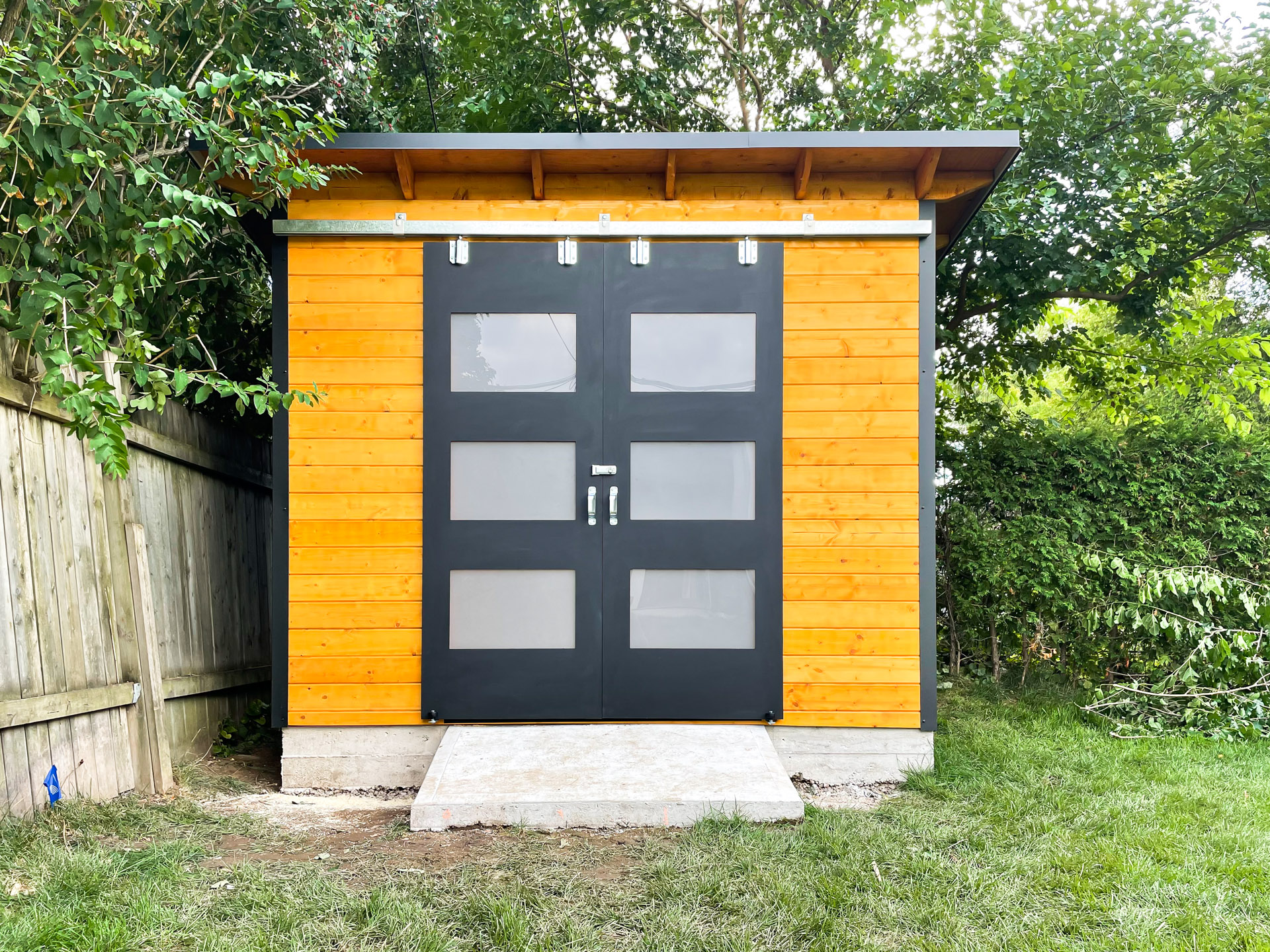 10x8 Essential Shed with jet black corrugated steel siding and Muskoka Brown pine front wall in Burlington Ontario, installed by Backyard Escape Studios.