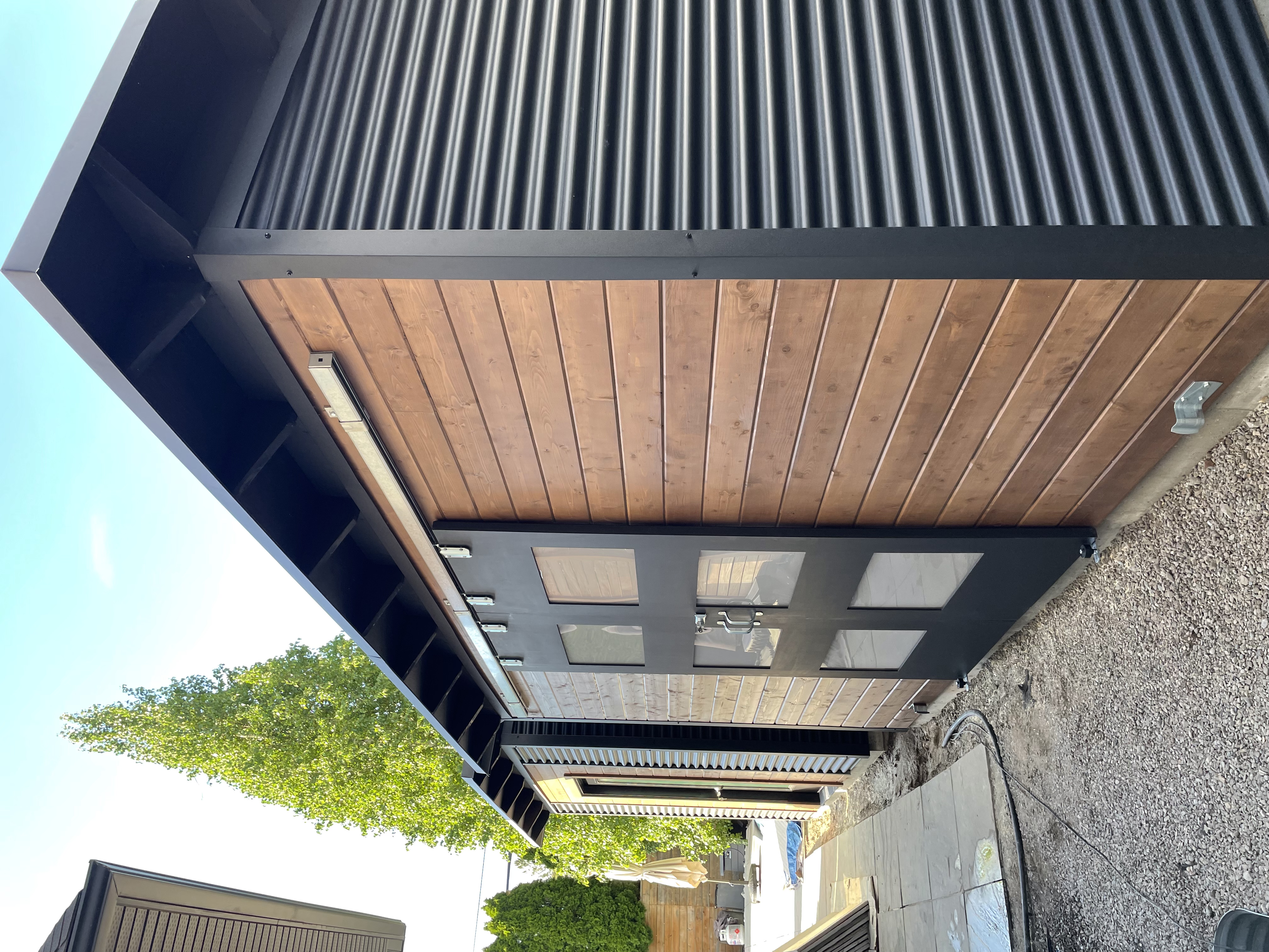 14x6 Essential Shed with Jet Black corrugated steel siding and double sliding barn doors with frosted Lexan glass windows in Etobicoke Ontario by Backyard Escape Studios.
