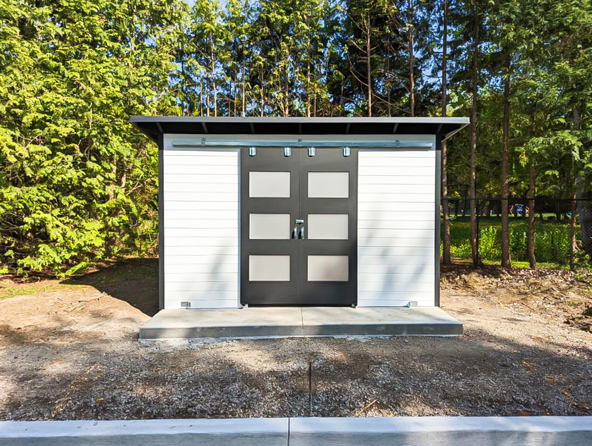 13x8 Essential Shed with White Satin pine T+G siding, Jet Black corrugated steel, and double sliding barn doors with frosted glass panels in Ancaster Ontario, installed by Backyard Escape Studios.