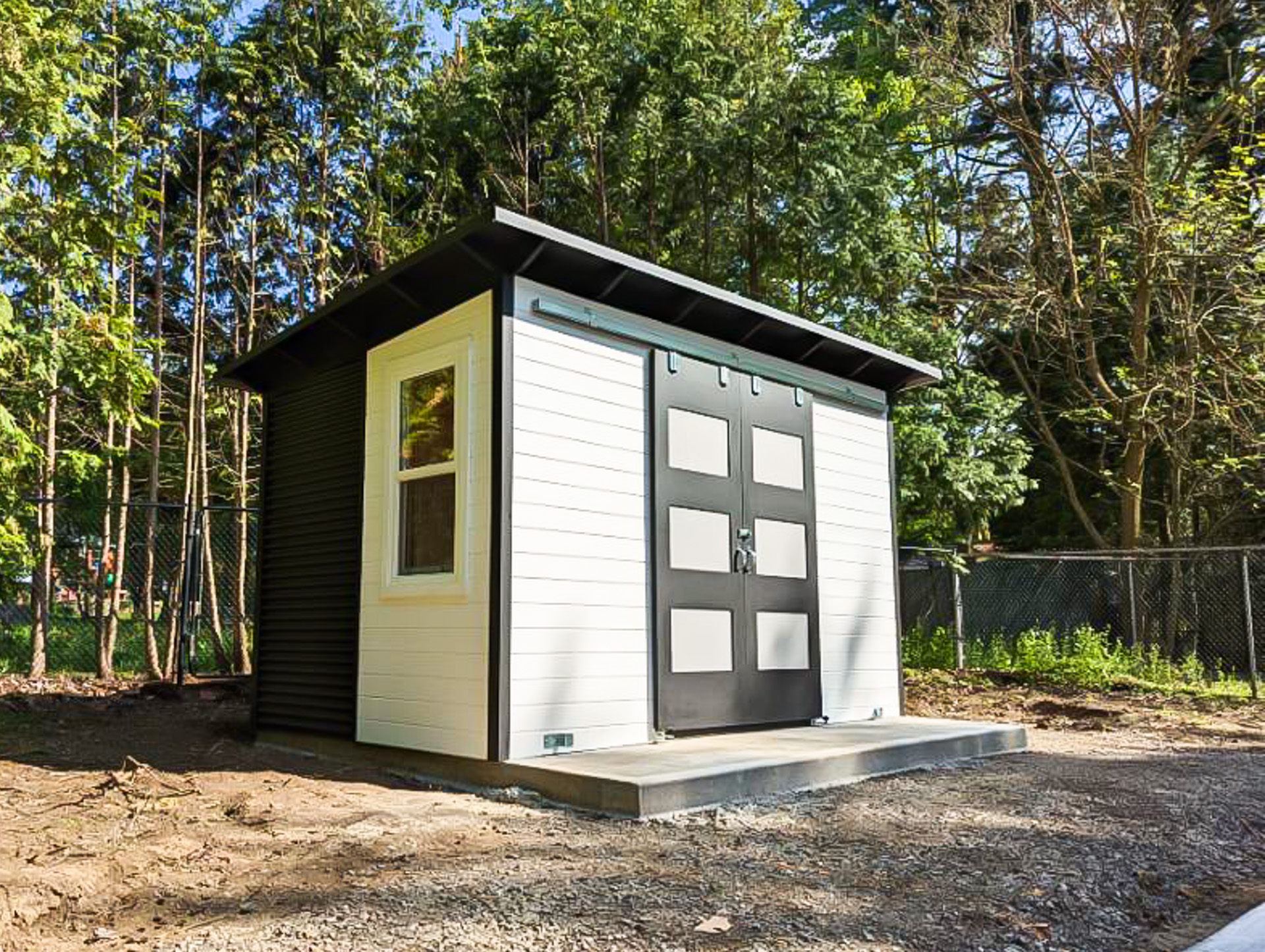 Side angle view of 13x8 Essential Shed in Ancaster Ontario showing the split siding detail with White Satin pine T+G upper half and Jet Black corrugated steel lower half, with a single-hung vinyl window, installed by Backyard Escape Studios.