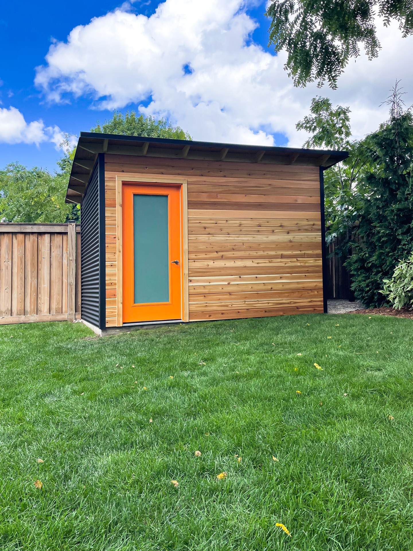 12x8 Essential Shed with black steel siding and cedar front installed in a Burlington Ontario backyard by Backyard Escape Studios.