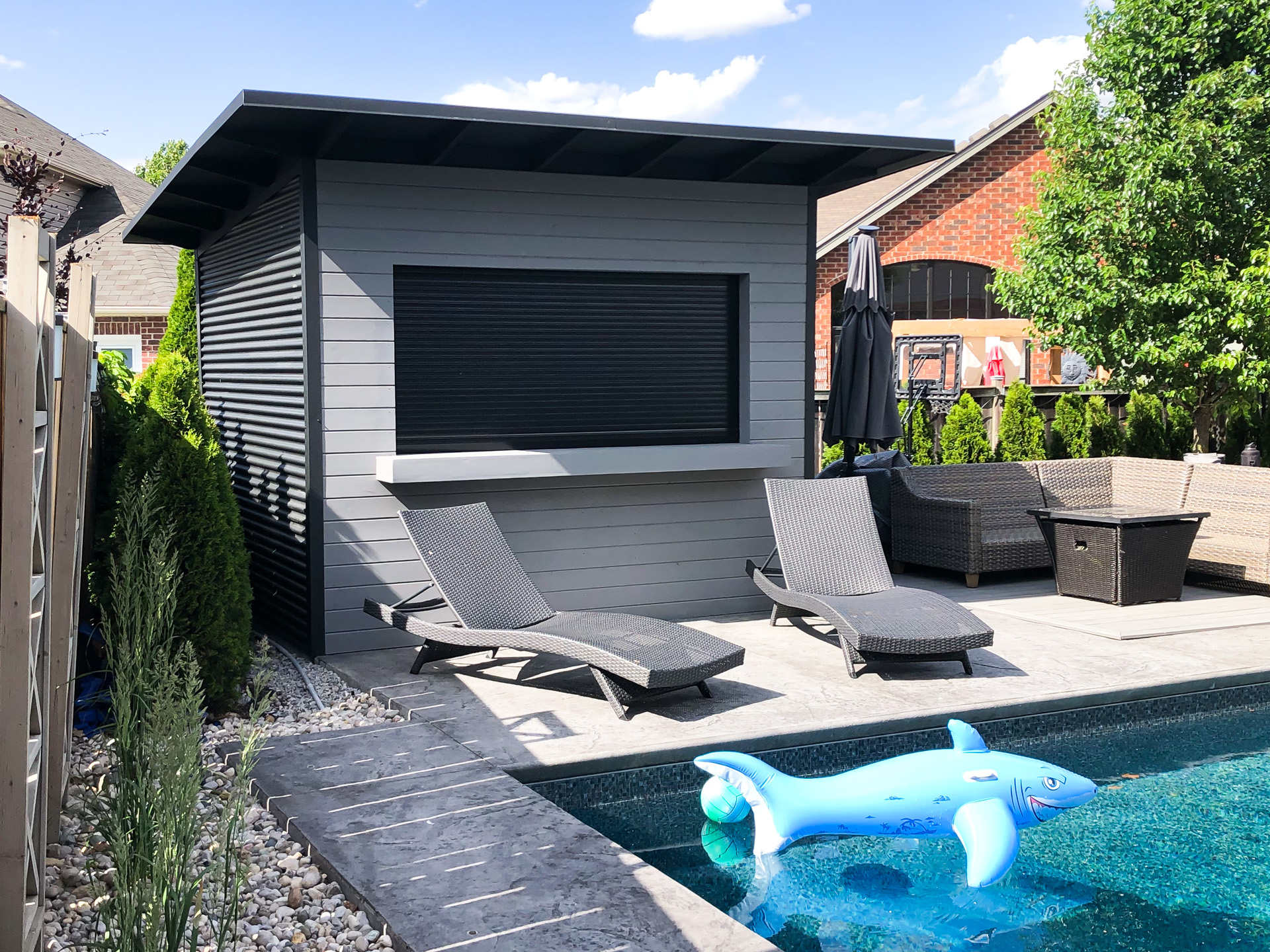 Side angle of 11x9.5 Advanced pool shed in London Ontario showing Jet Black corrugated steel siding and extended roof overhang, installed by Backyard Escape Studios.