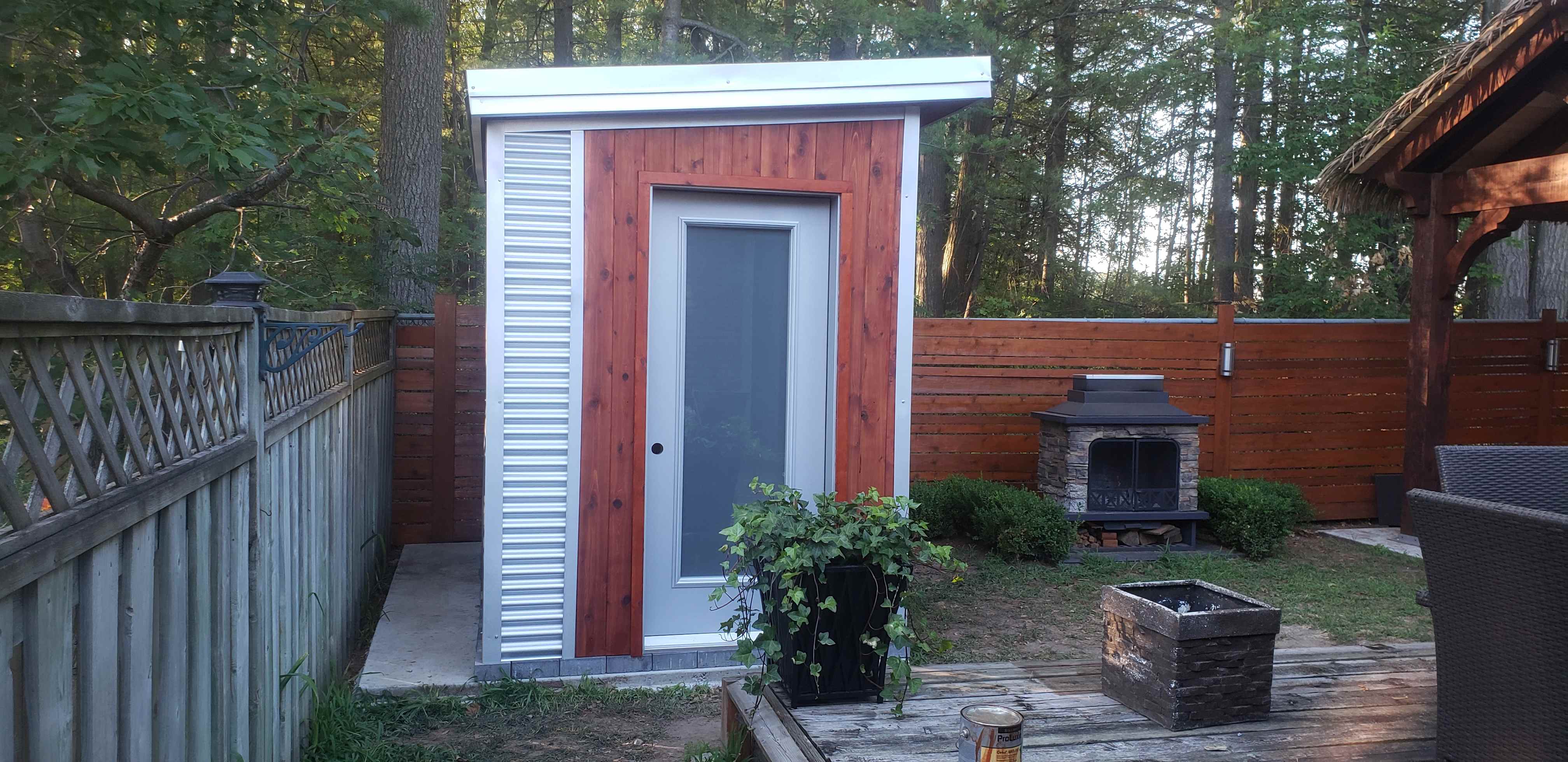 9x6 sauna shed with tight knot cedar front wall, Galvalume corrugated steel siding, and full-lite glass panel door in Barrie Ontario, installed by Backyard Escape Studios.