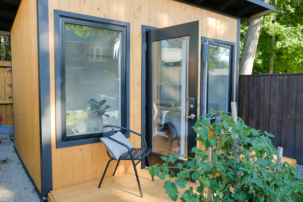 Side view of 12x9 Backyard Office Studio showing large windows, glazed door with keypad lock, and cedar siding with dark trim in Toronto Ontario, built by Backyard Escape Studios.