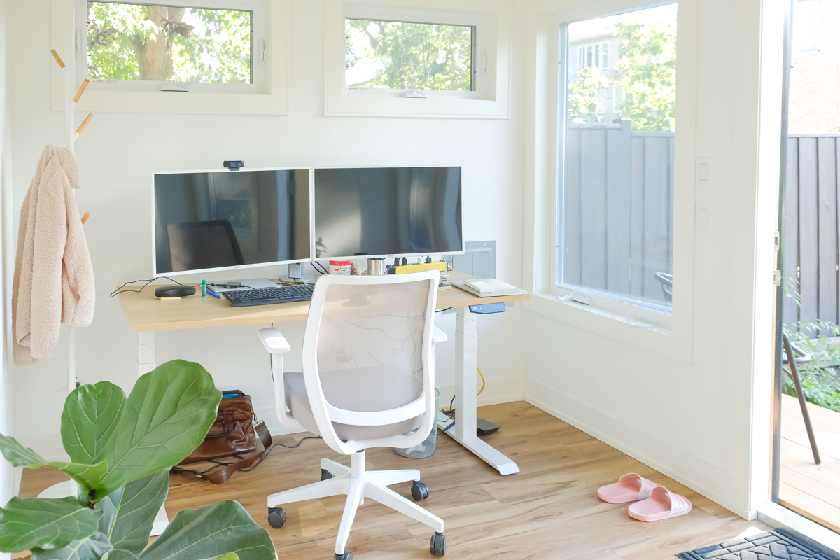 Interior workspace of 12x9 Backyard Office Studio in Toronto Ontario with standing desk, dual monitors, clerestory windows, and hardwood floors, built by Backyard Escape Studios.