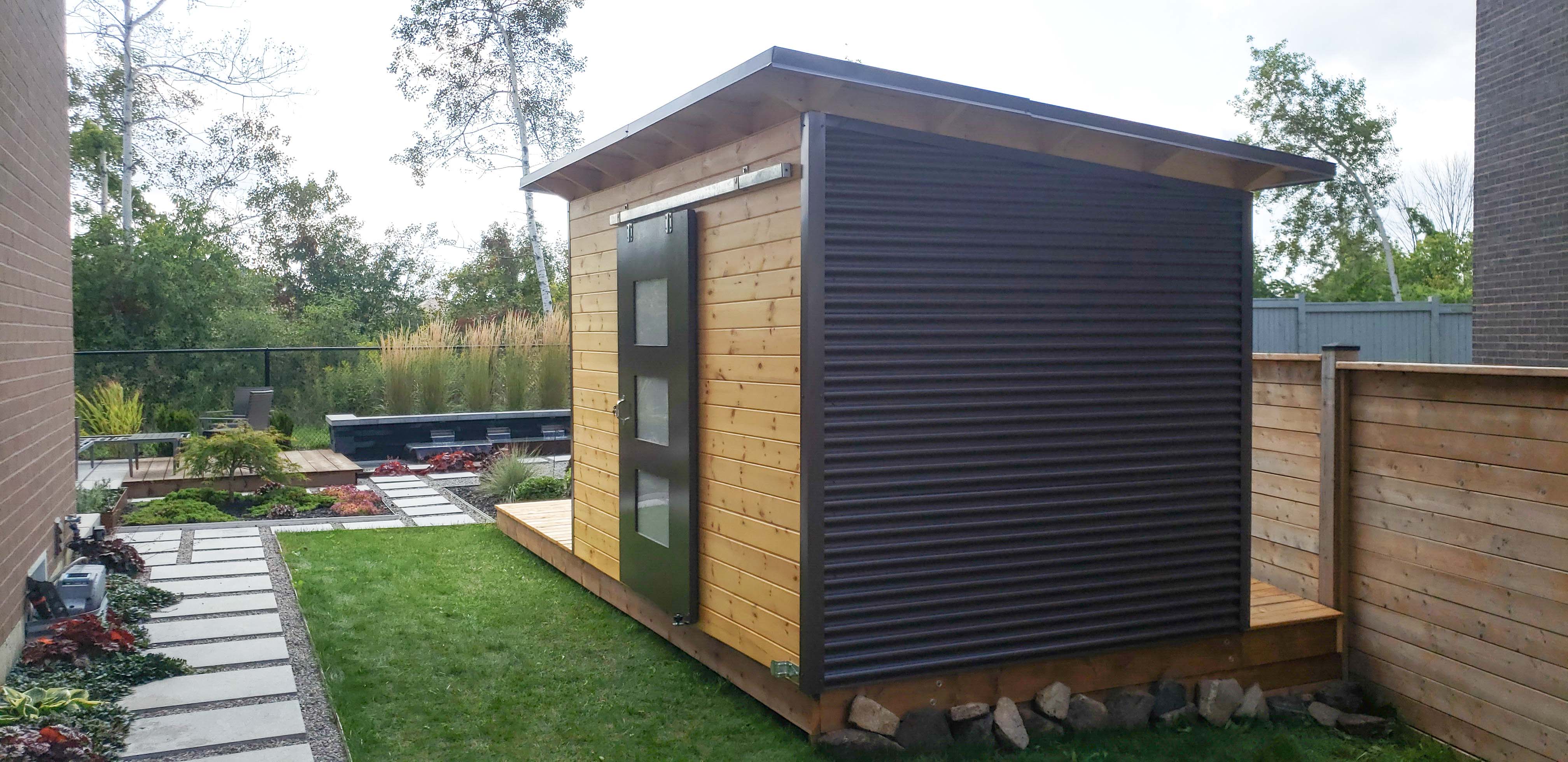 Front view of 12x8 Essential garden shed in Richmond Hill Ontario showing centred 48-inch sliding barn door with three Lexan glass panels and teak-stained horizontal pine front wall, built by Backyard Escape Studios.