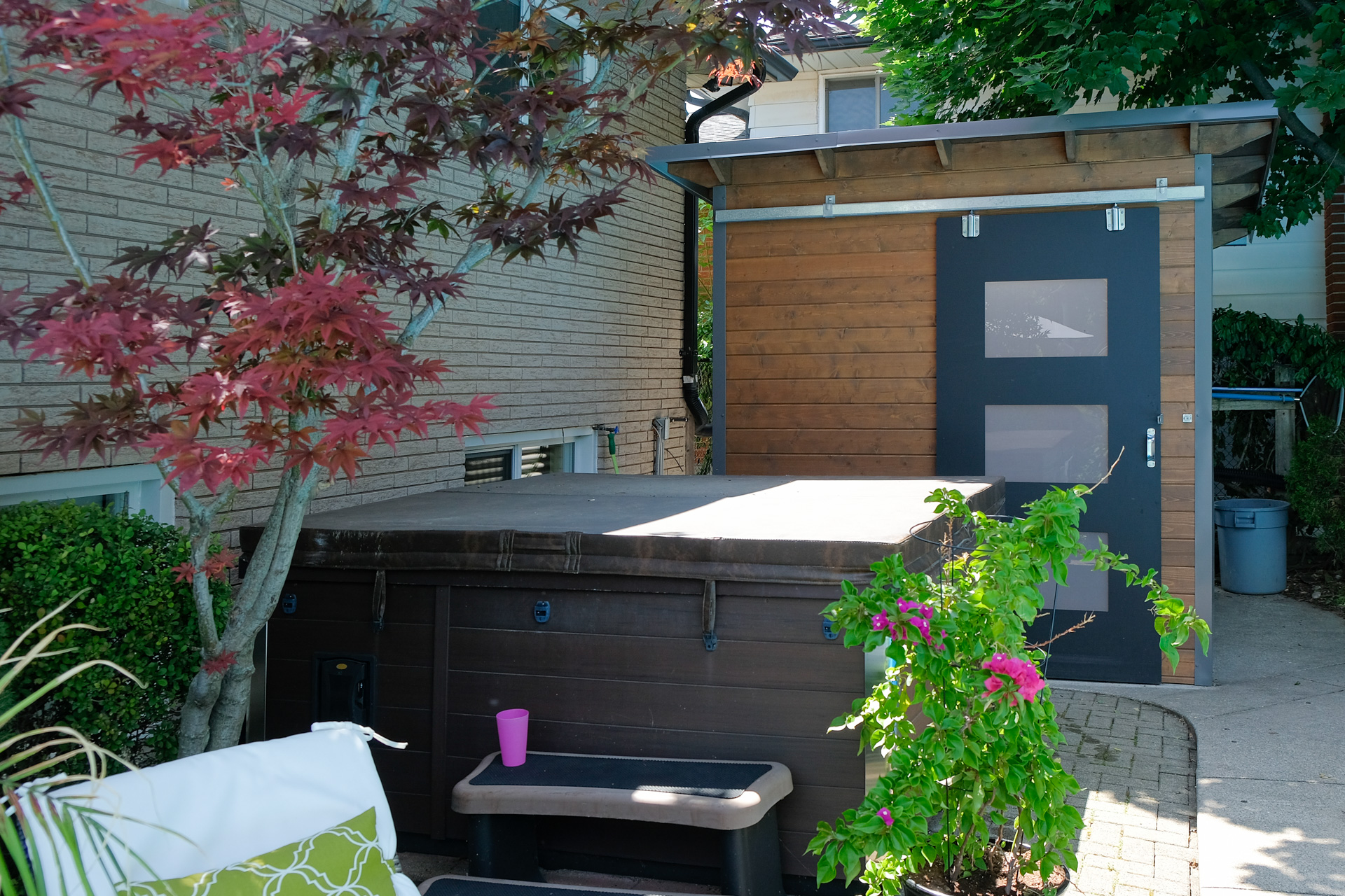 Front view of 8x8 Essential Pool Shed in Hamilton Ontario showing 42-inch sliding barn door with frosted Lexan glass windows and exposed stained rafters, installed by Backyard Escape Studios.