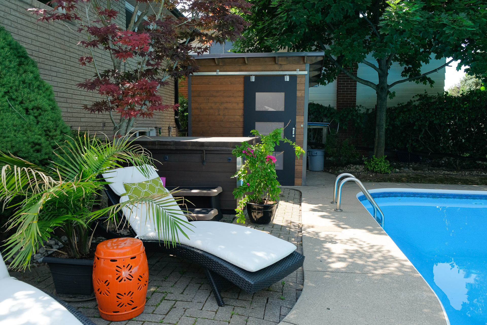 8x8 Essential Pool Shed installed poolside in Hamilton Ontario backyard with charcoal steel siding, warm pine front wall, and exposed overhead rafters, installed by Backyard Escape Studios.