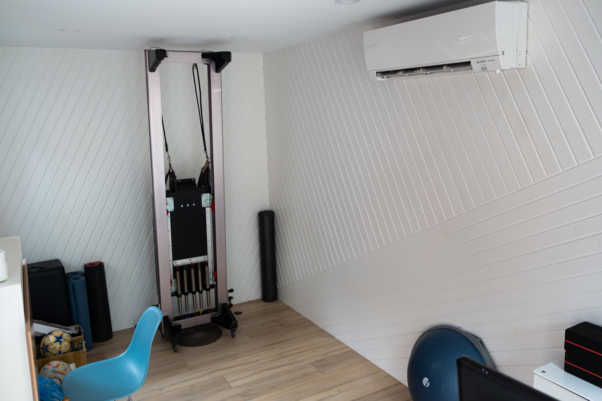 Interior of 16x9 EcoShed backyard studio in Toronto Ontario with white painted pine T+G walls, LVP flooring, and Mitsubishi mini-split installed by Backyard Escape Studios.