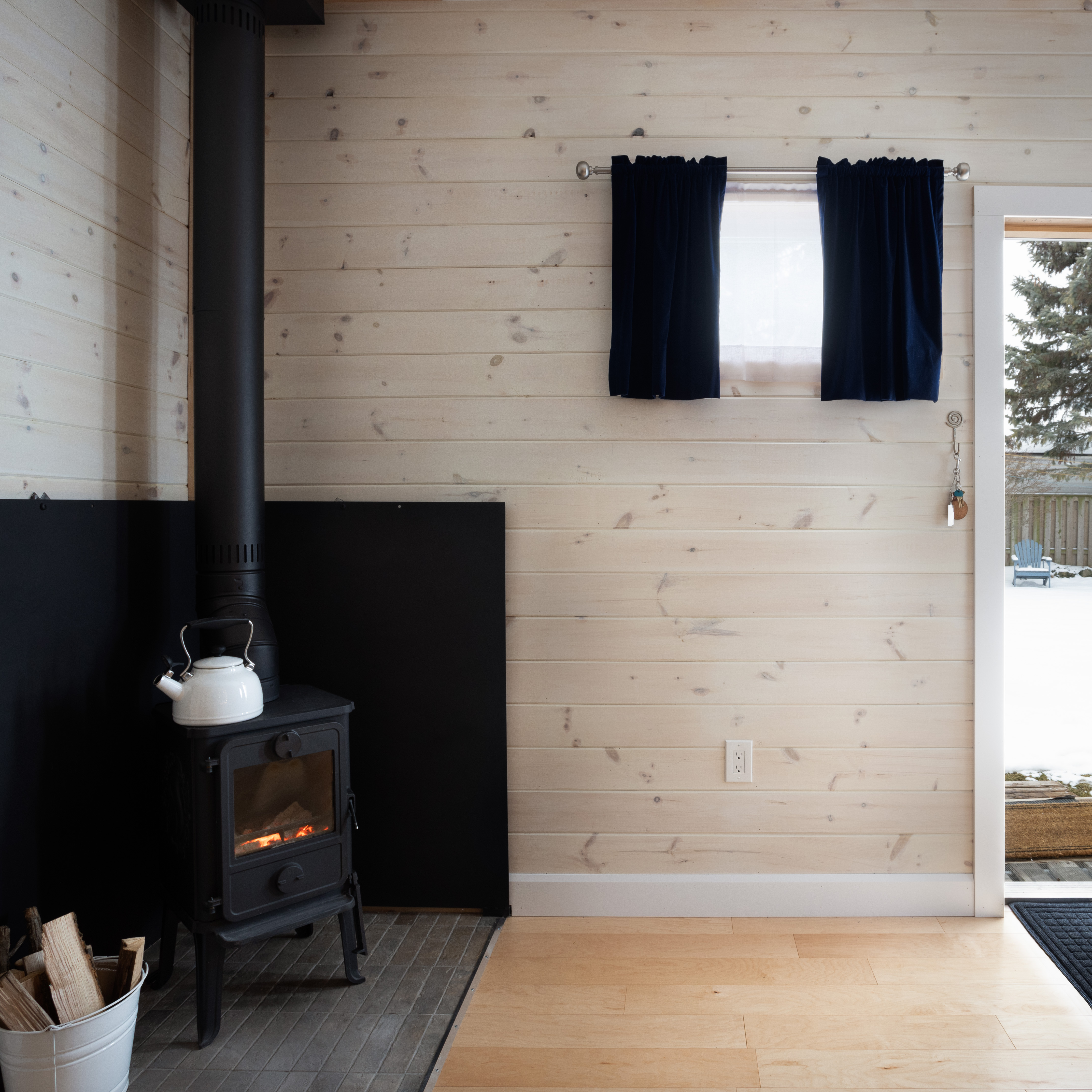 Backyard silversmith studio with pine shiplap siding and wood stove chimney in a snowy Ontario winter backyard by Backyard Escape Studios