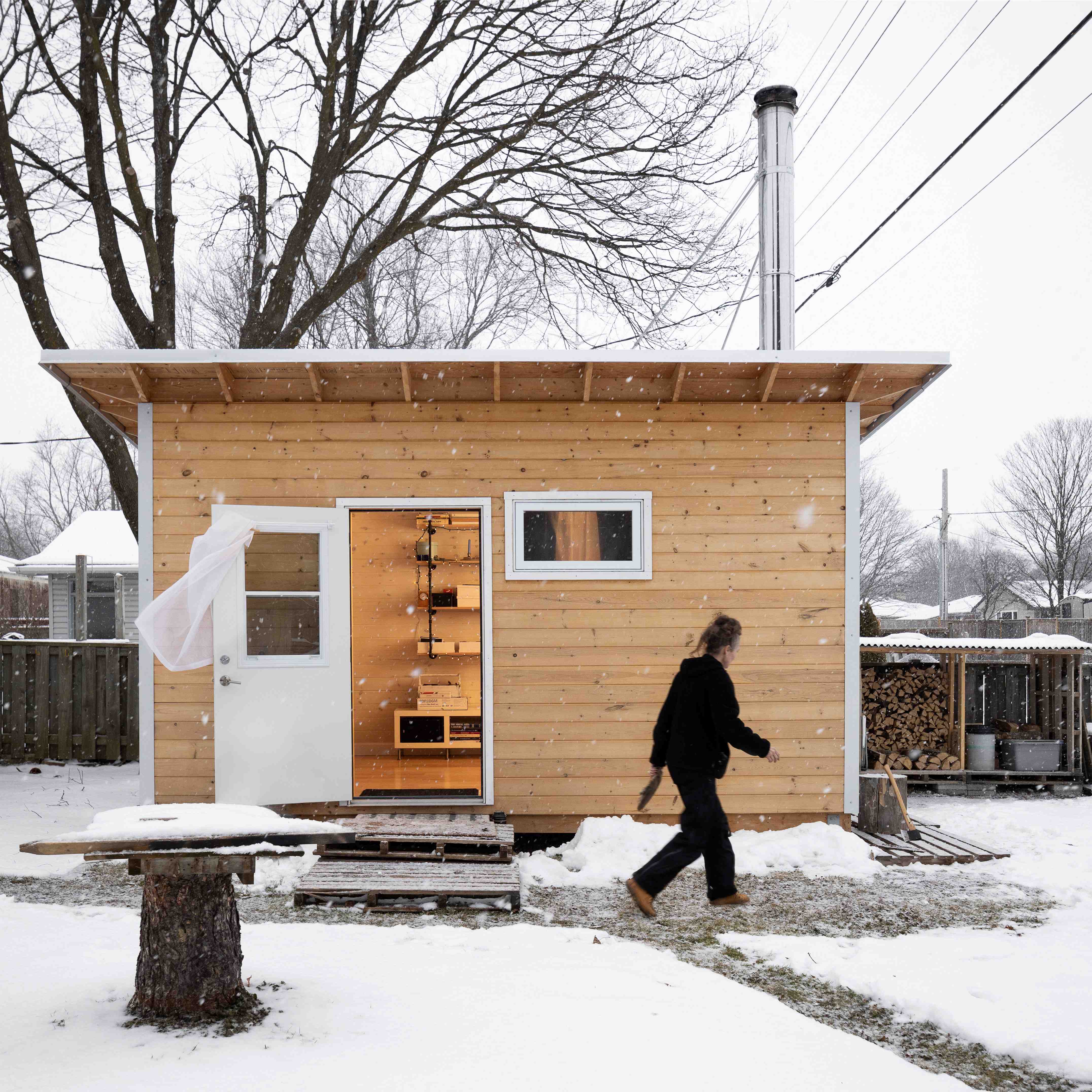 Backyard silversmith studio with pine shiplap siding and wood stove chimney in a snowy Ontario winter backyard by Backyard Escape Studios