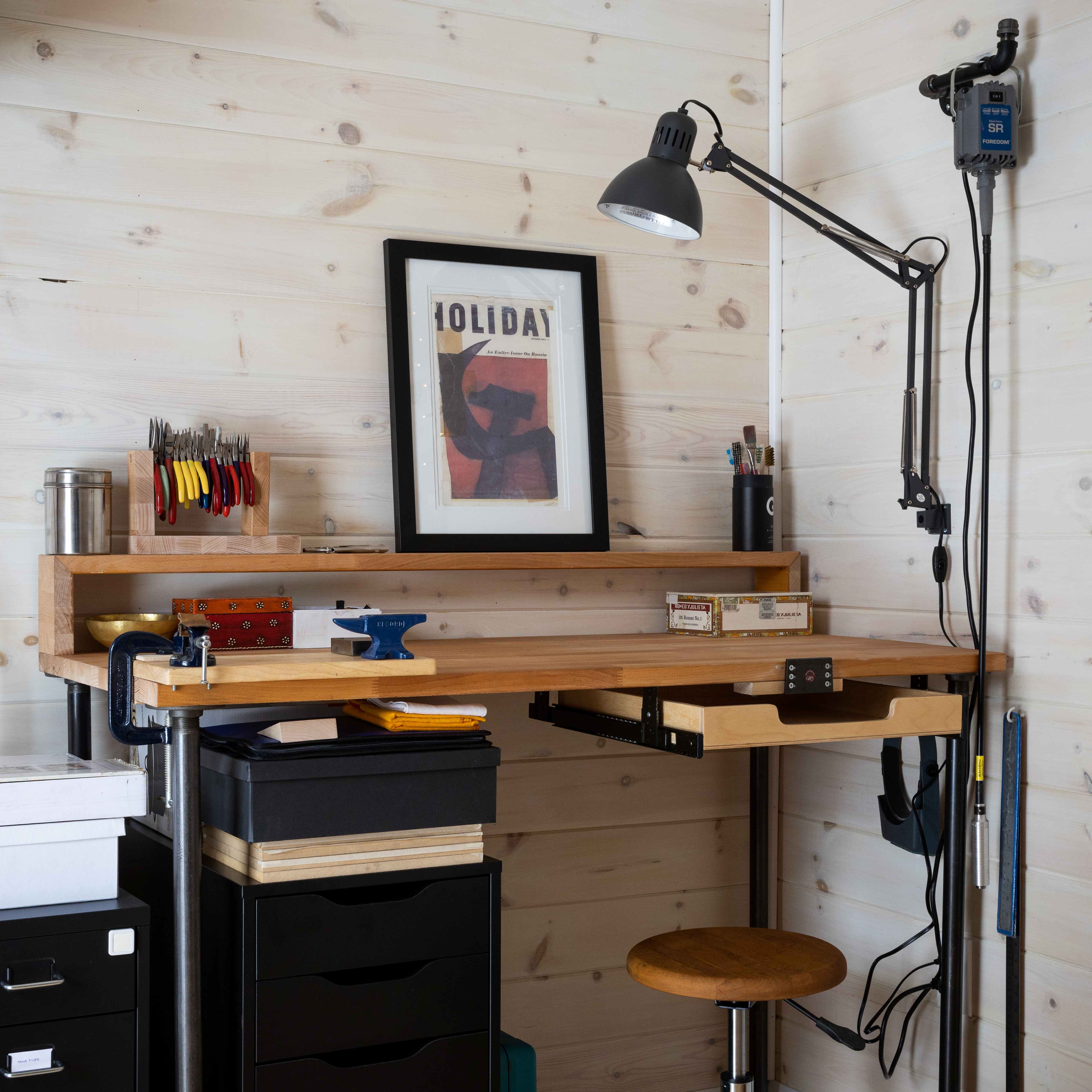 Custom jewelry workbench inside a backyard silversmith studio with light pine walls, task lighting, jeweler tools, and Foredom flex shaft in Ontario