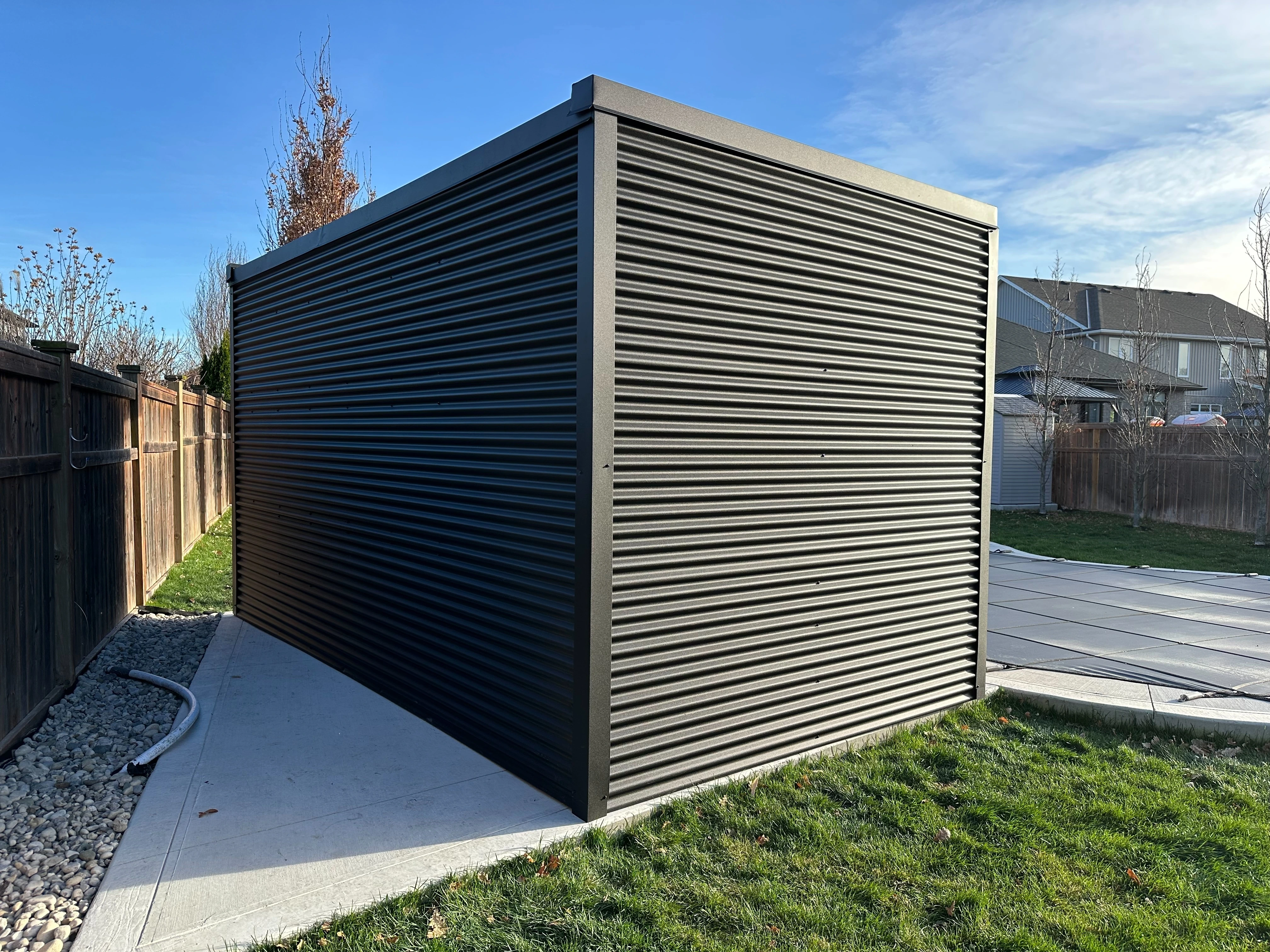 Jet black 7/8 inch corrugated steel siding on the back wall of a 16x9 Pool Cabana installed in Sarnia, Ontario.