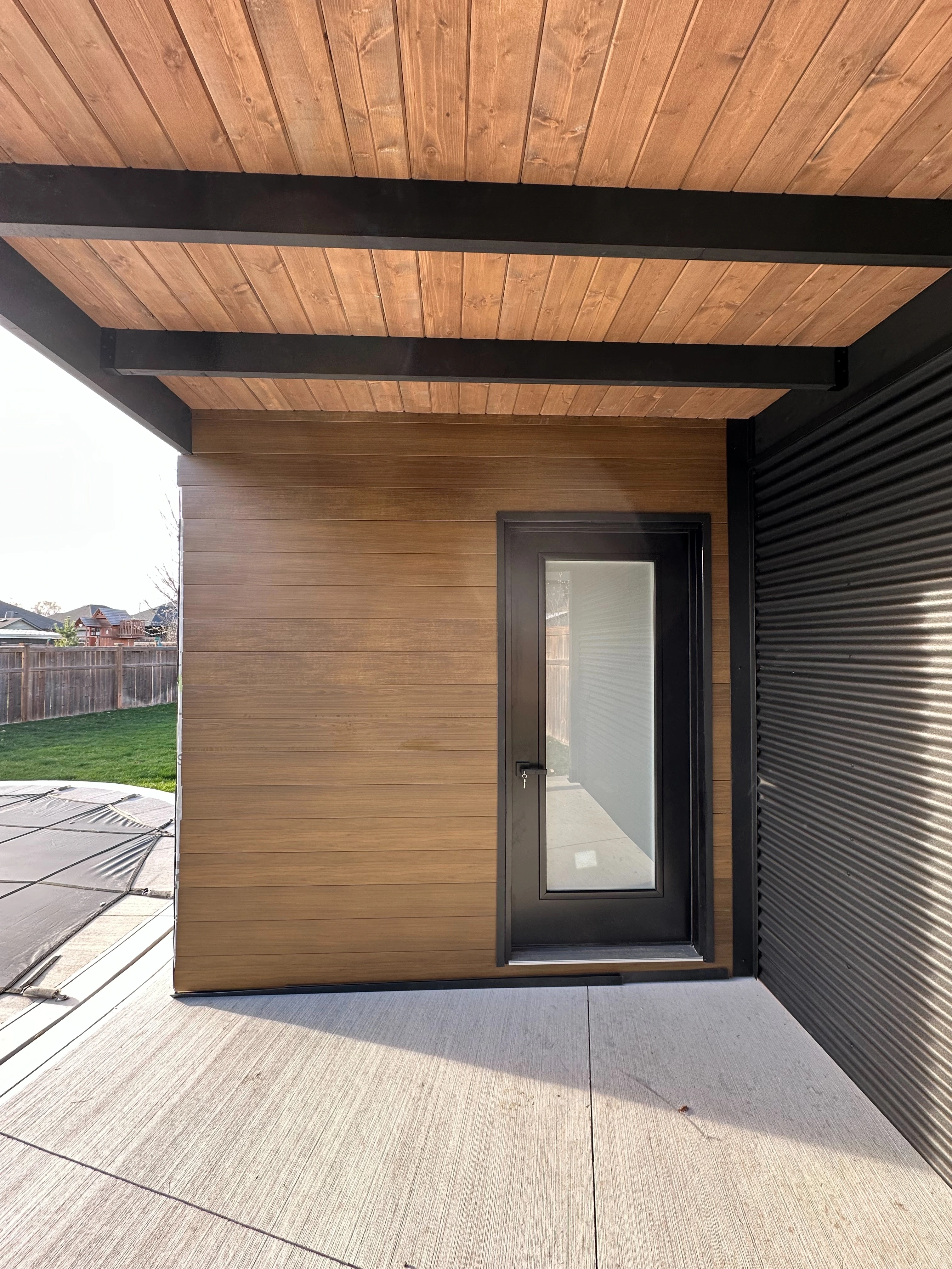 Frosted glass change room door and Muskoka Brown pine ceiling under the pavilion of a 16x9 Pool Cabana in Sarnia, Ontario.