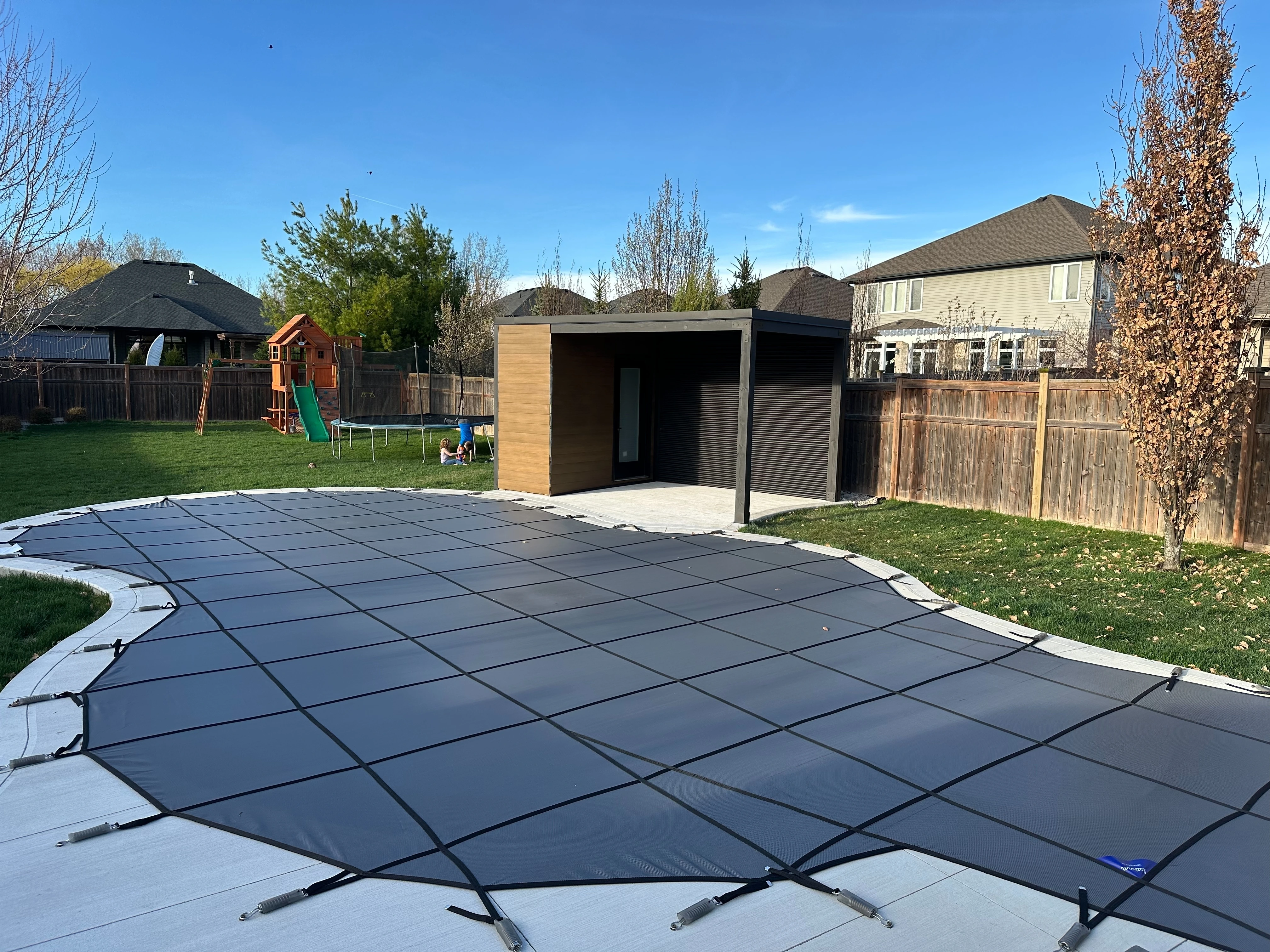 16x9 Pool Cabana in jet black corrugated steel and teak shiplap installed beside an in-ground pool in Sarnia, Ontario.