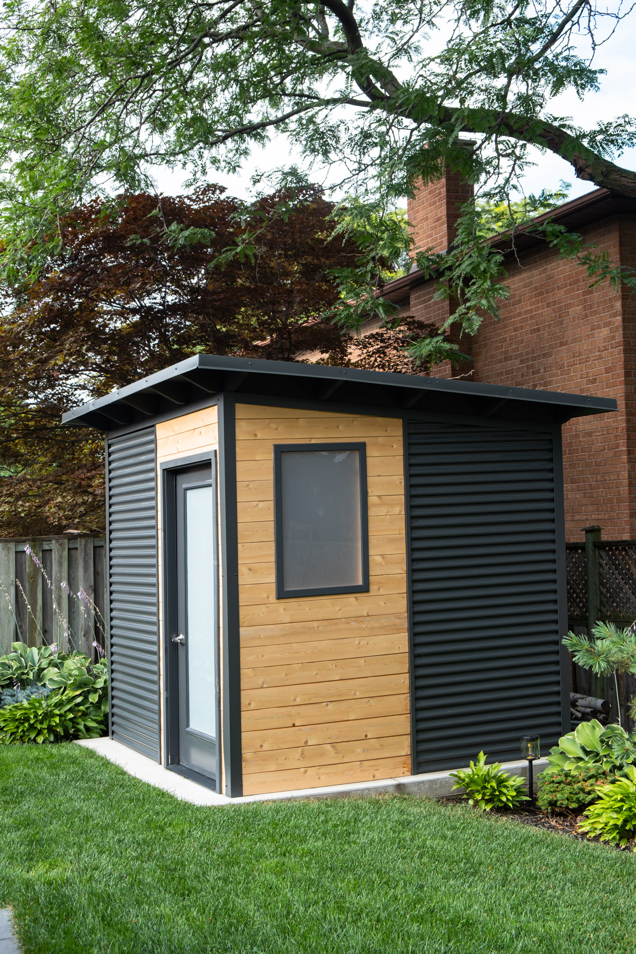 Side view of an 8x8 Garden Shed in Etobicoke Ontario showing the cedar accent panel and frosted Lexan window, an Essential Shed by Backyard Escape Studios.
