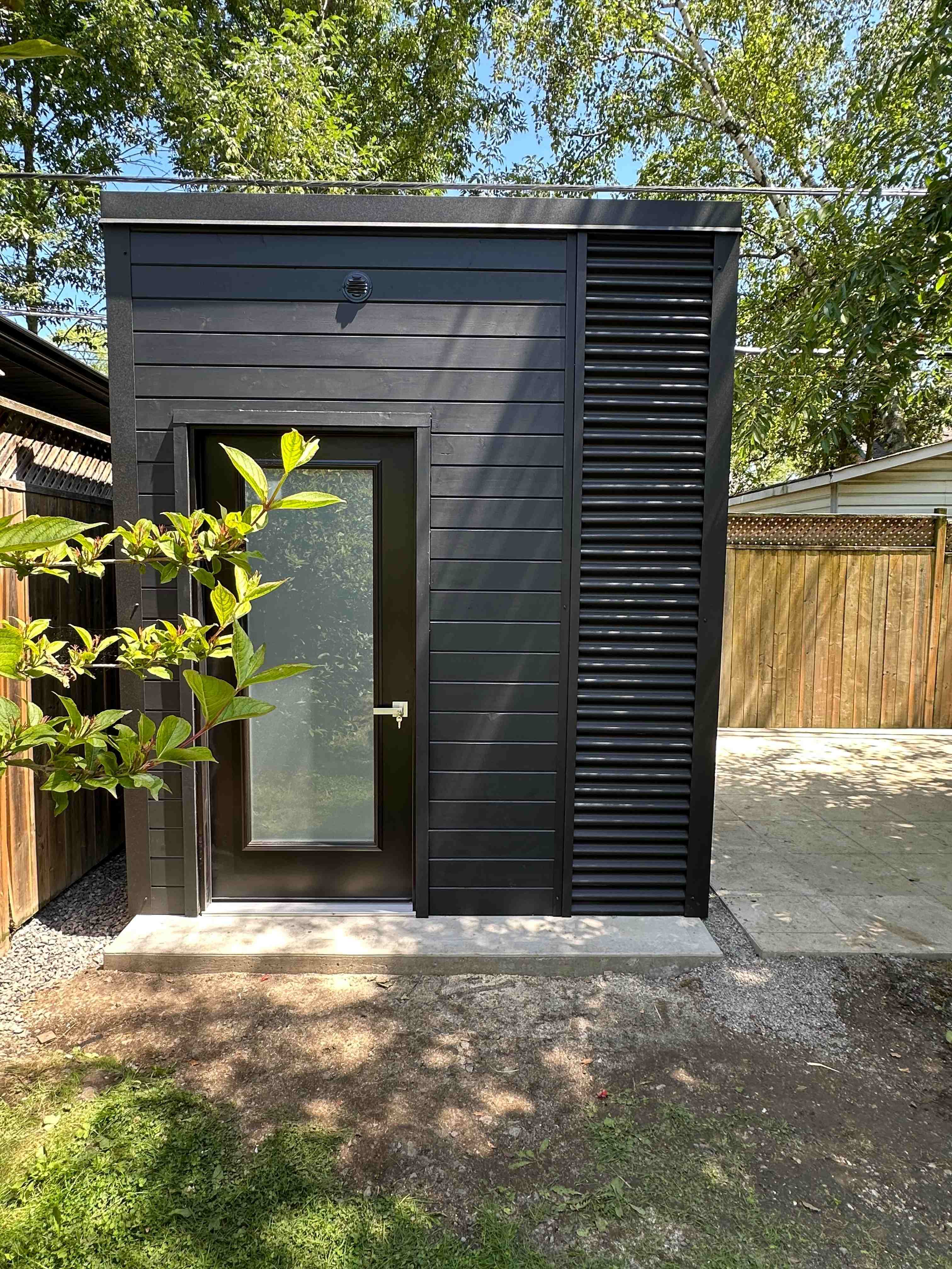 8x12 Modern Shed styled Cube Shed with black beauty pine siding and corrugated steel accent in Etobicoke, Ontario, installed by Backyard Escape Studios.