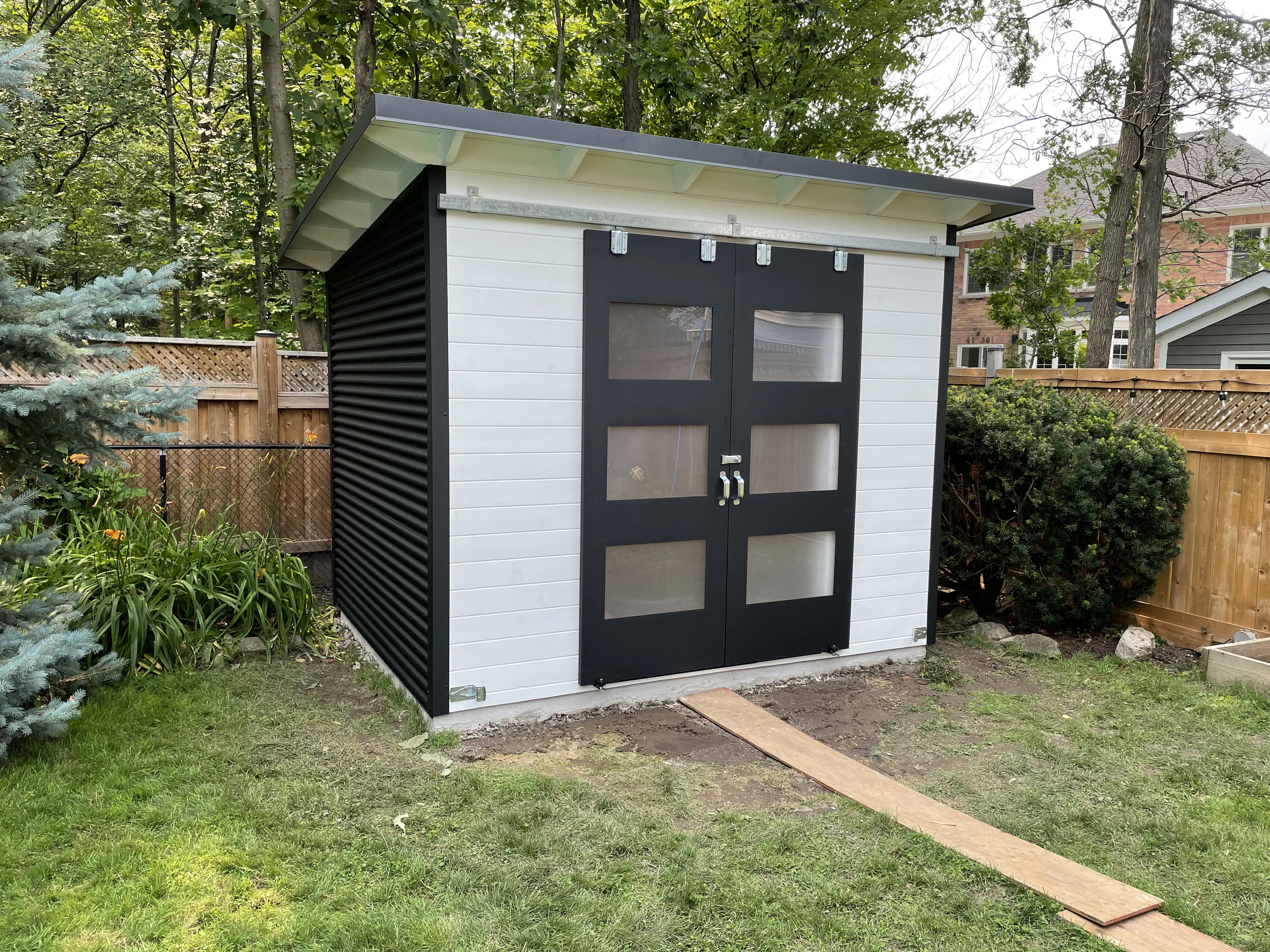 10x8 Essential storage shed with white pine front and black corrugated steel siding in Burlington, Ontario, installed by Backyard Escape Studios.