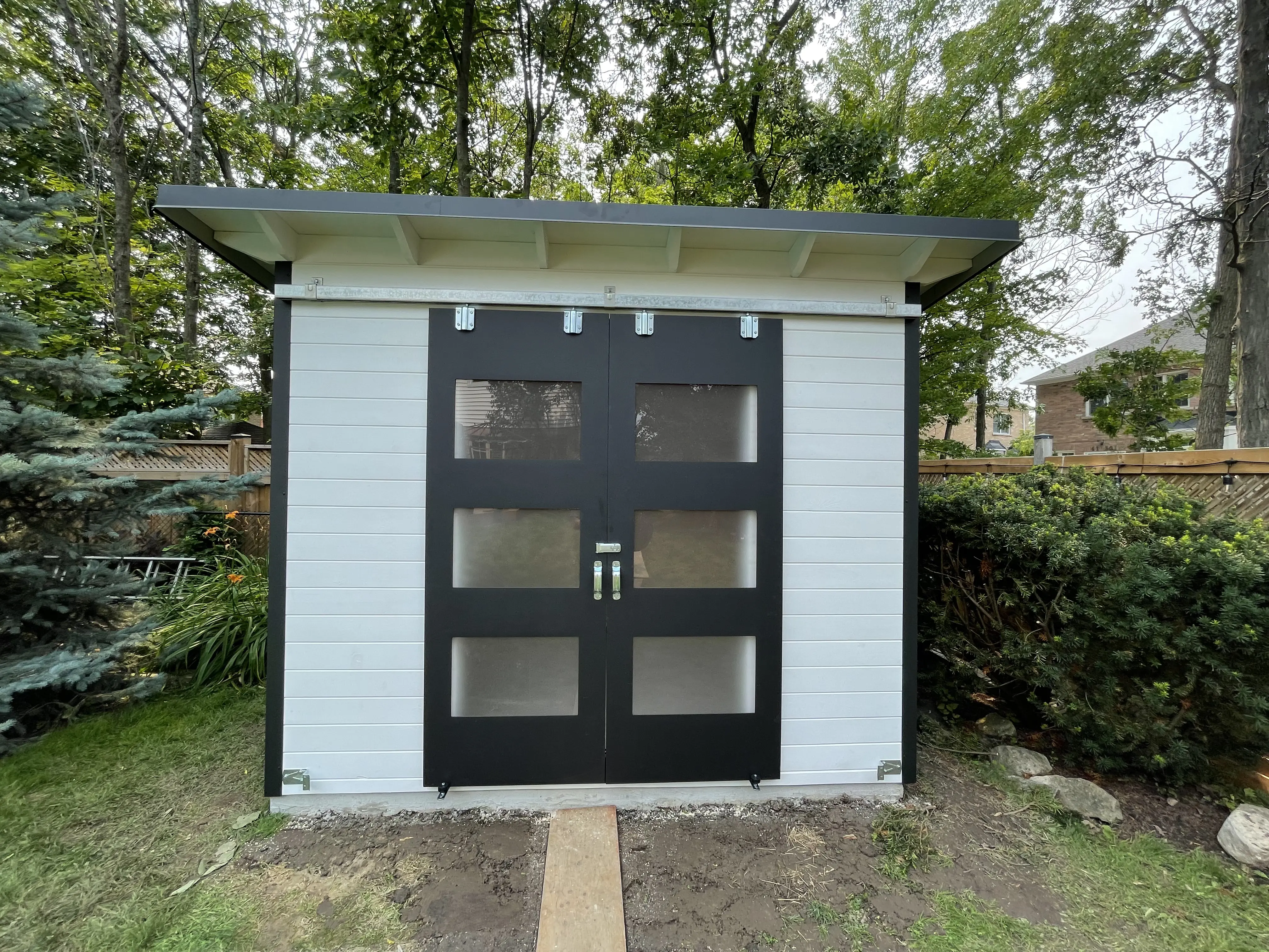 10x8 storage shed with white pine front and black sliding barn doors in Burlington, Ontario.