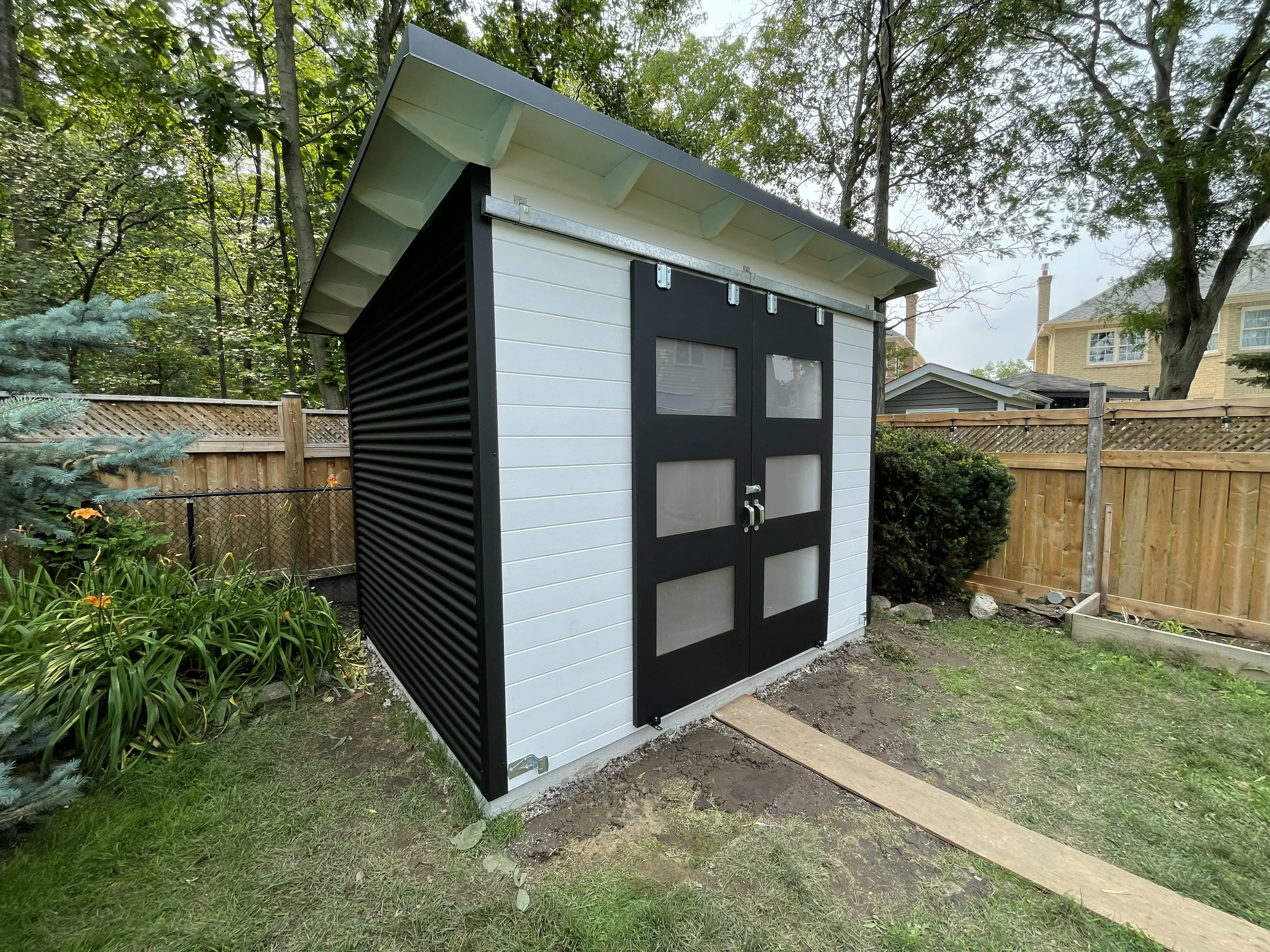 10x8 Essential Shed showing black corrugated steel side siding against white front in Burlington, Ontario.