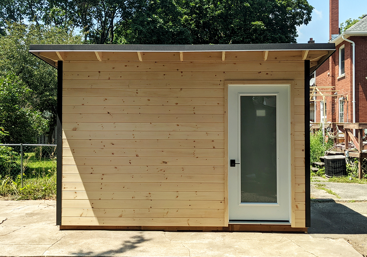 Front view of a 12x8 Garden Shed with natural pine T+G front and frosted glass inswing door in Stratford, Ontario.