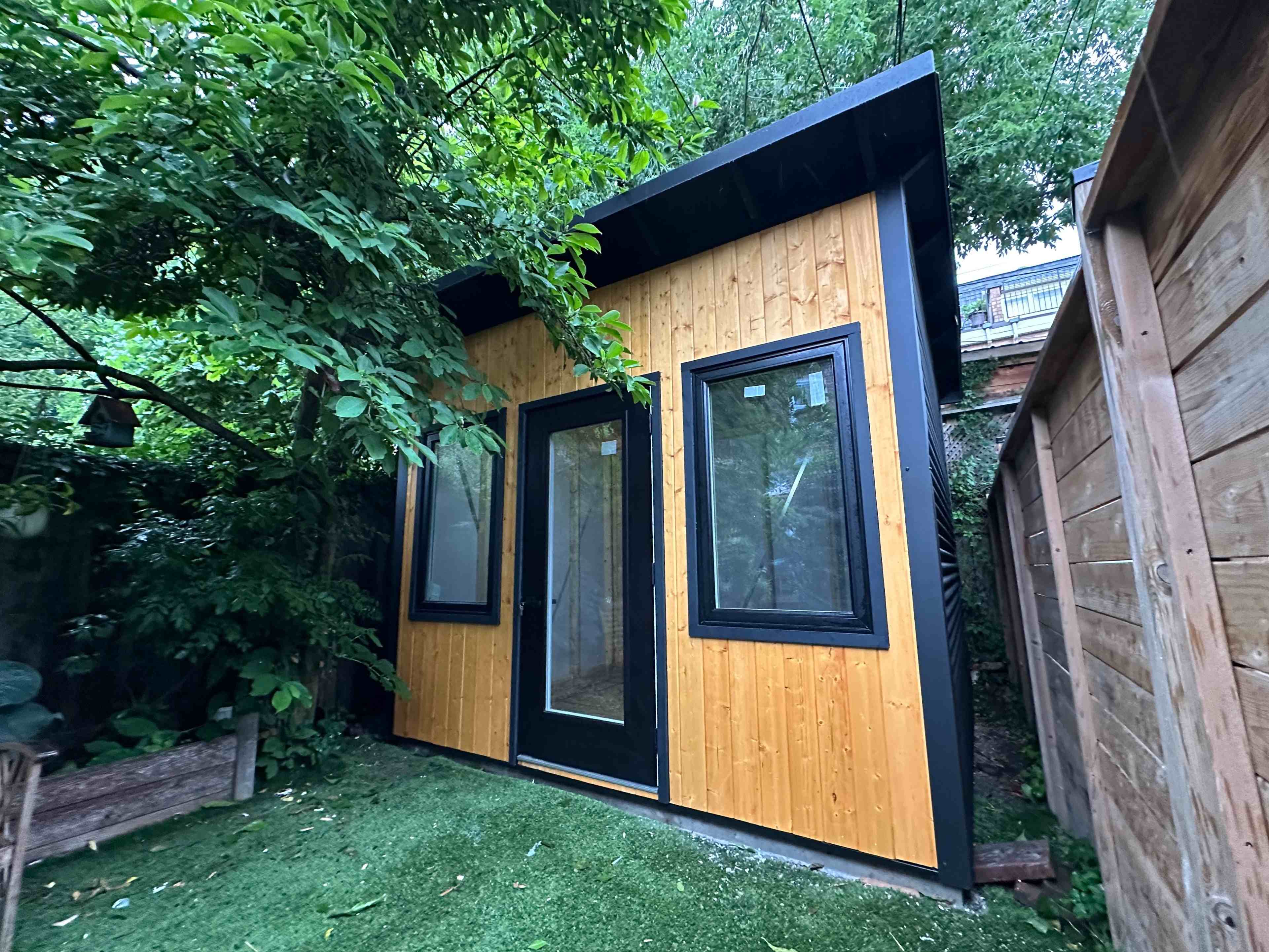 11x9 Backyard Office studio with cedar-stained pine front and black steel siding in Toronto, Ontario, installed by Backyard Escape Studios.