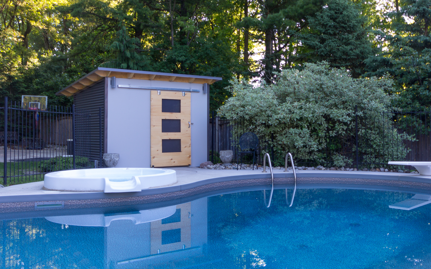 12x8 Essential Pool Shed with charcoal siding installed poolside in London, Ontario, installed by Backyard Escape Studios