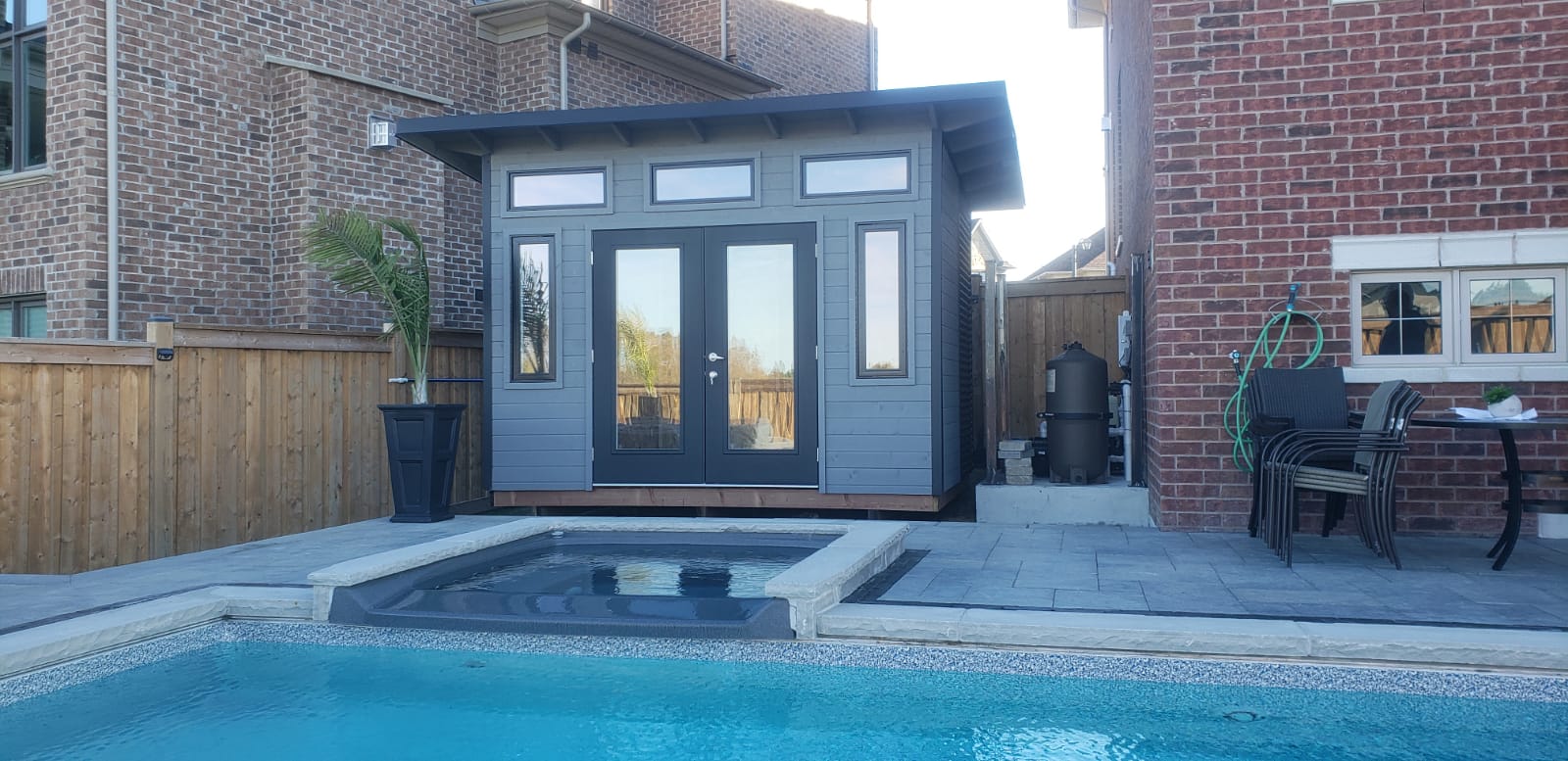 12x8 Advanced Shed pool shed with black French doors and transom windows viewed across the pool in King City Ontario