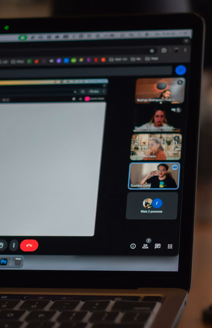 Laptop screen showing a video call with multiple participants in a sidebar chat window.
