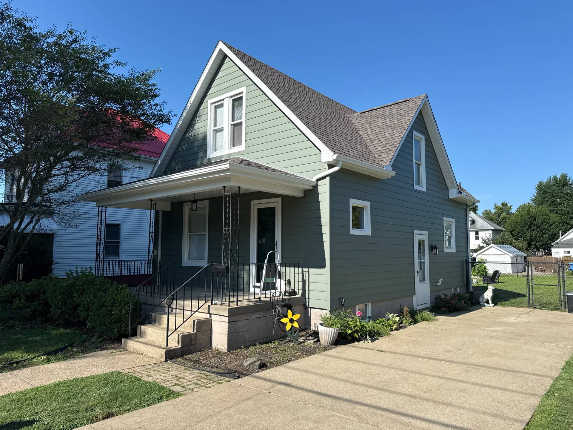 renovated home with green siding and new shingles
