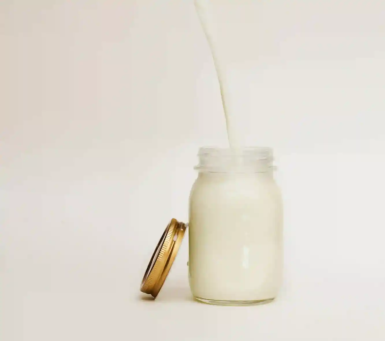 a glass jar with a white liquid pouring into it