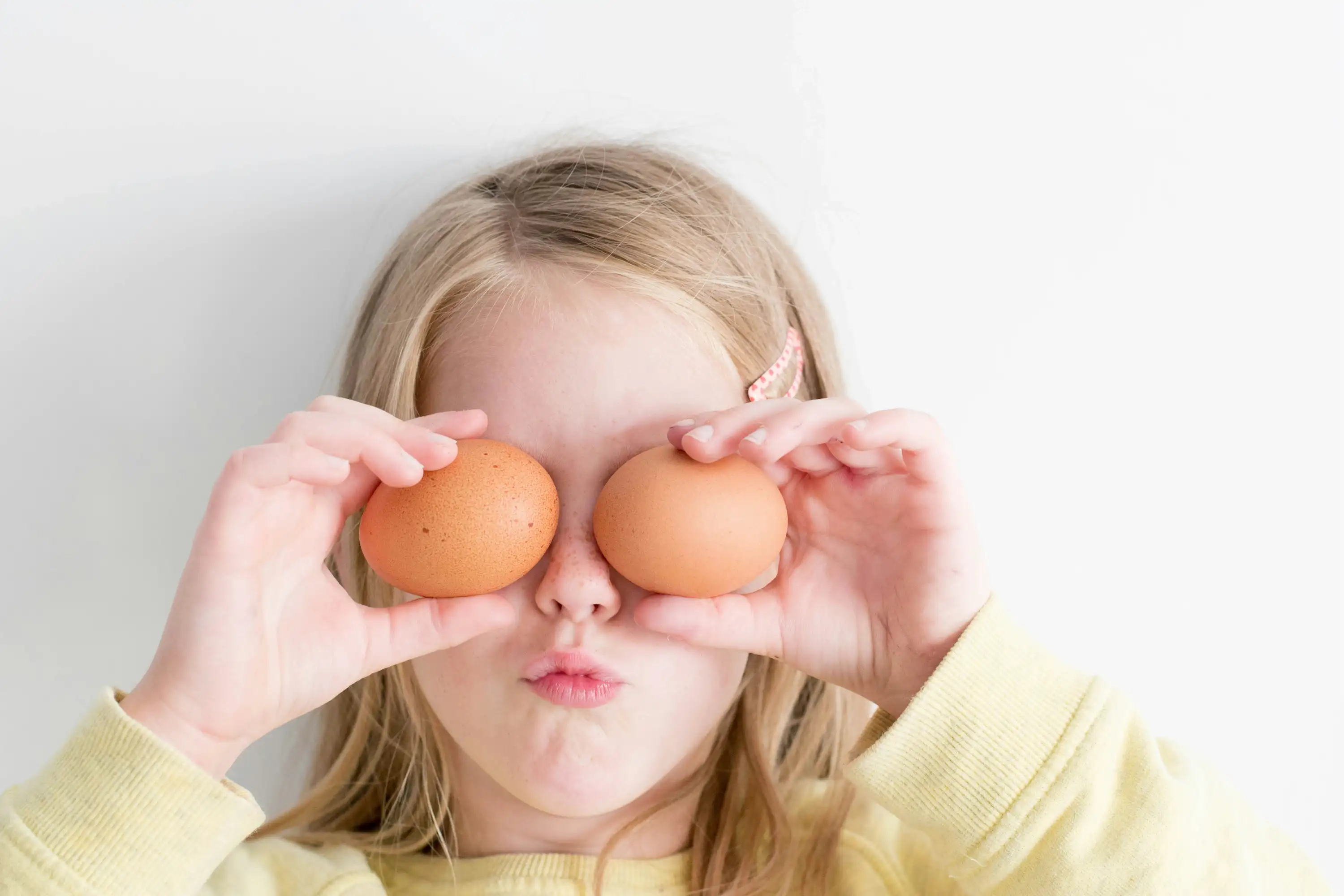 a girl holding two eggs over her eyes