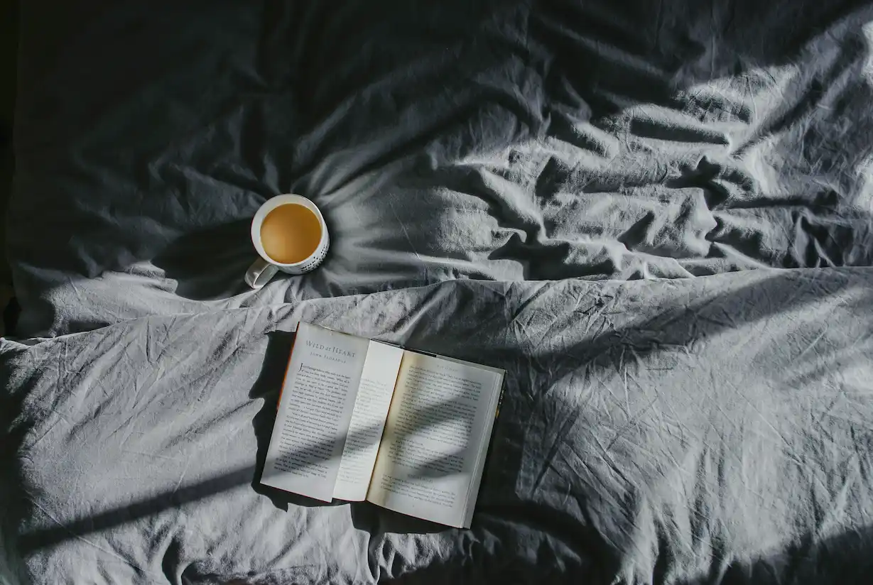 a book and a cup of coffee on a bed