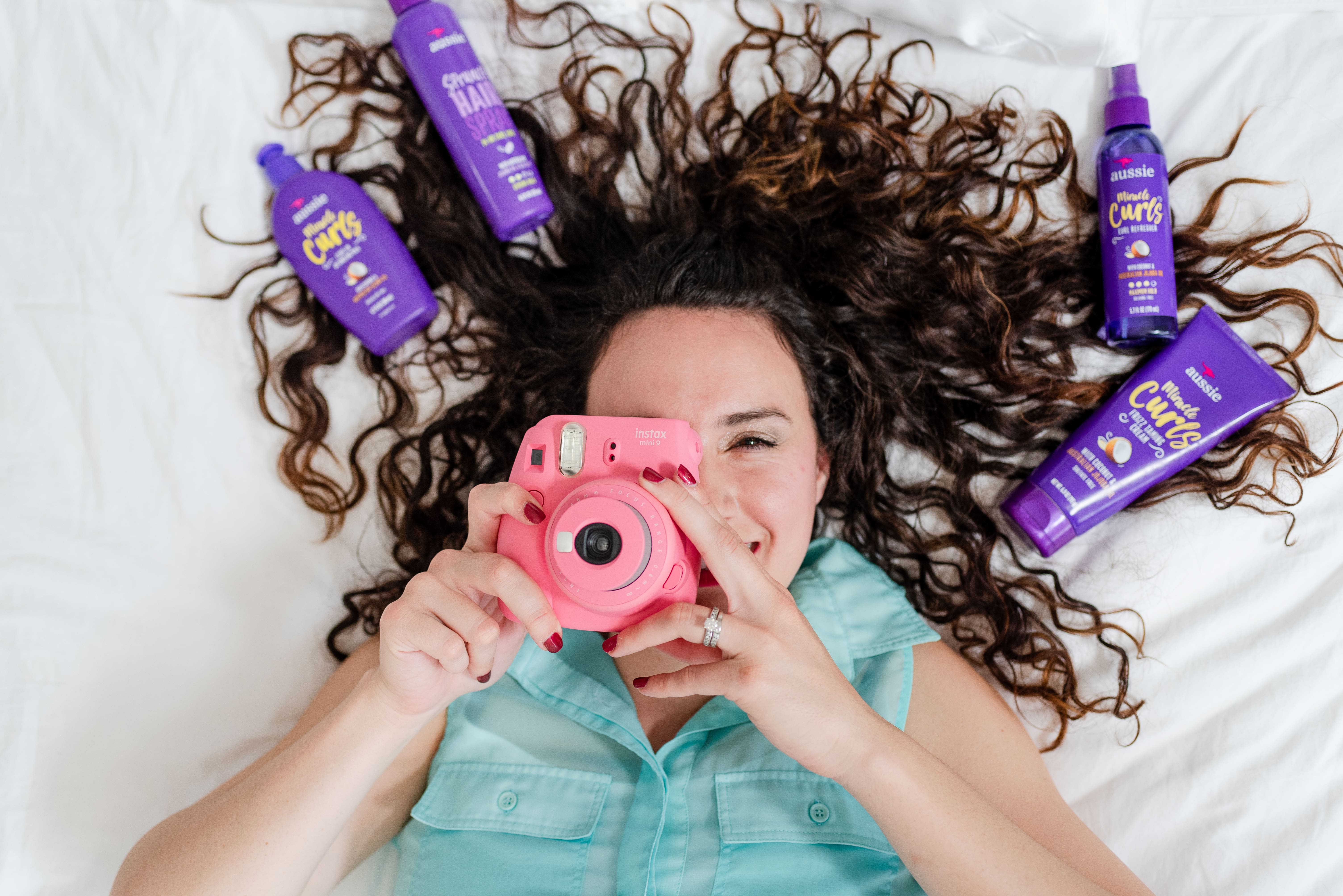 a woman taking a picture with hair products around her