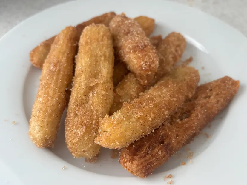 Cinnamon-sugar churros piled on a white plate