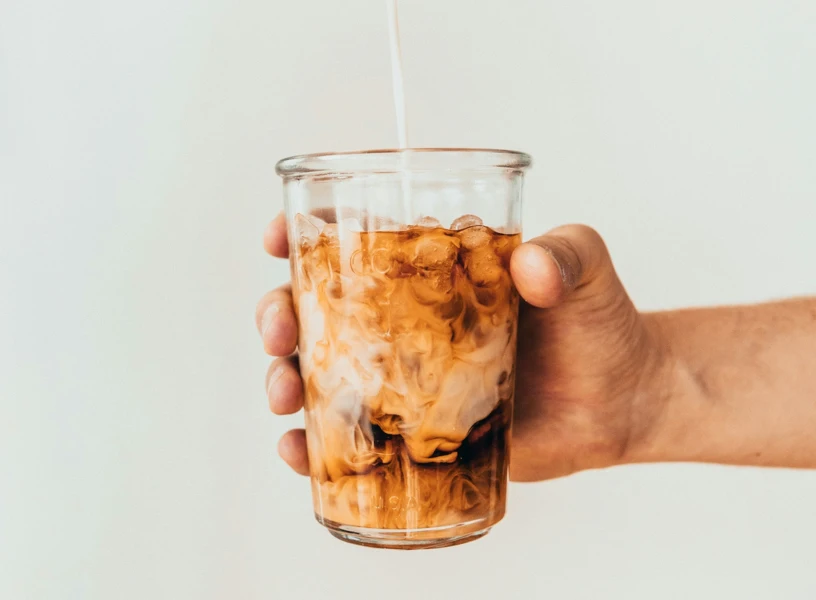 Hand holding a glass of chai-infused cold brew with milk