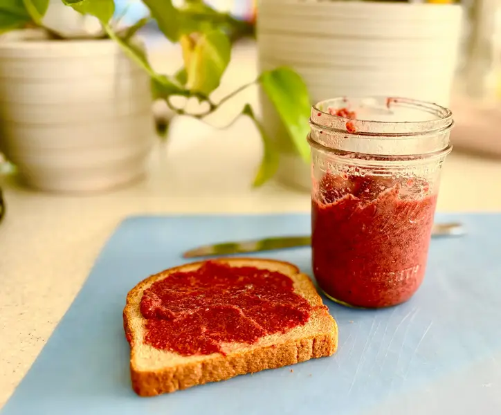 Toast spread with strawberry chia jam next to a jar of jam