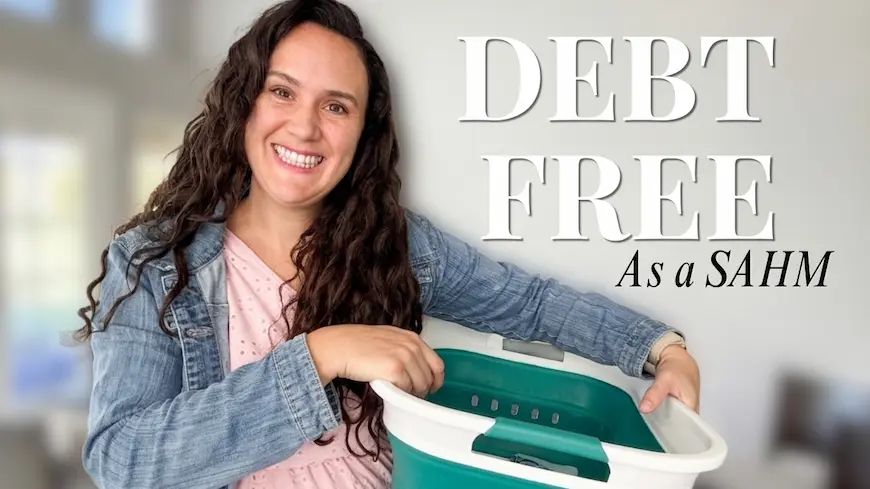 Smiling mom holding a laundry basket beside the words "Debt Free as a SAHM"