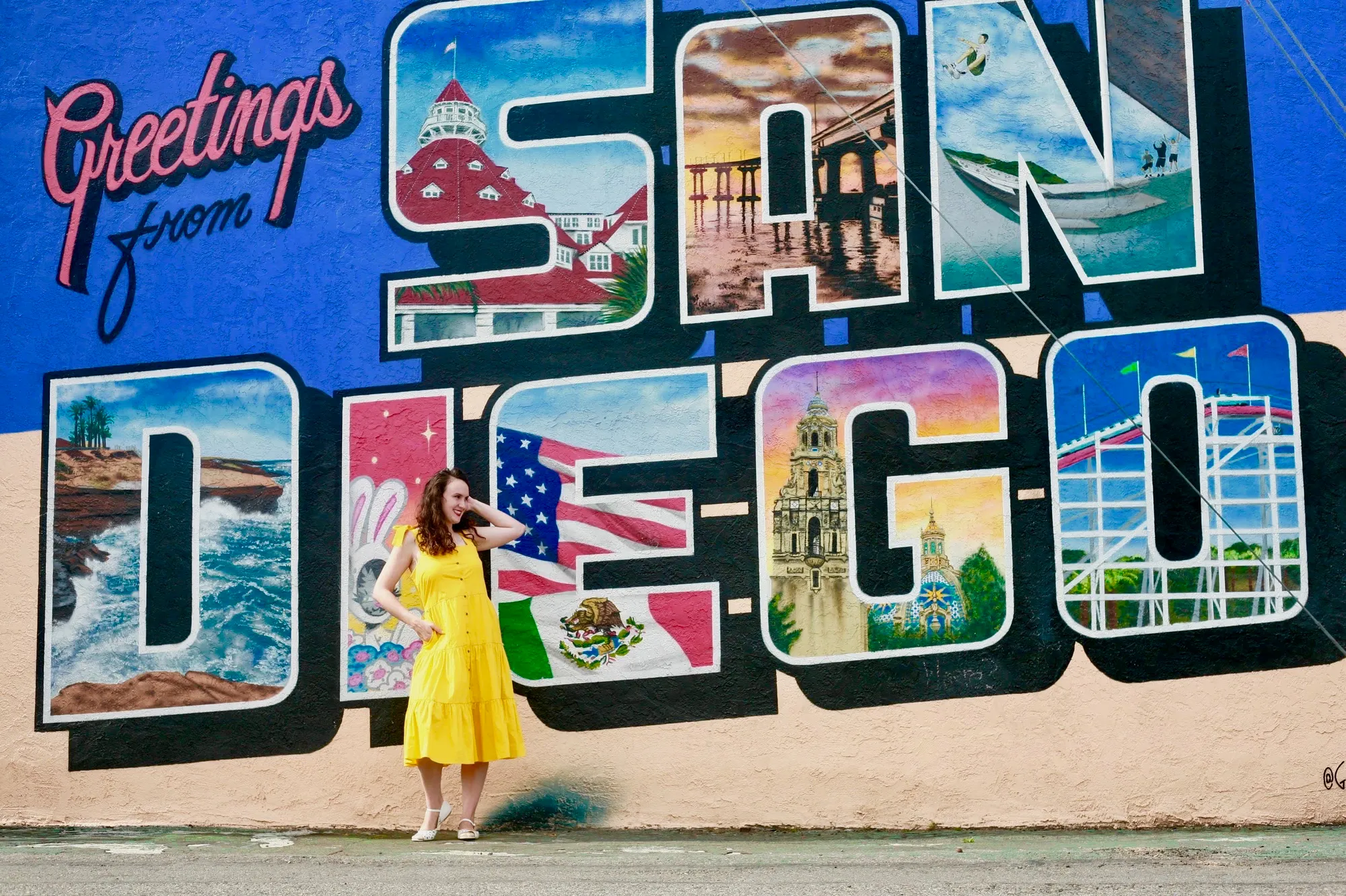 a woman in a yellow dress standing in front of a mural