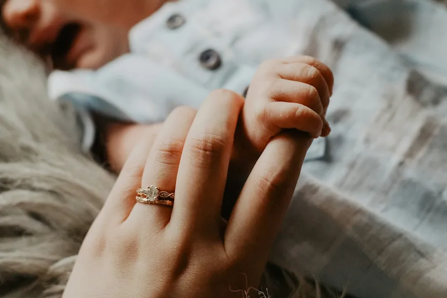 Newborn's tiny hand holding a parent's finger