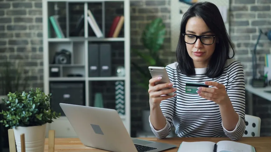 Woman at a desk with a laptop and phone, working on a budget