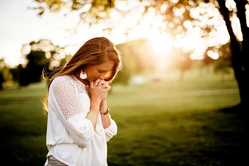 Woman praying outdoors in golden evening light