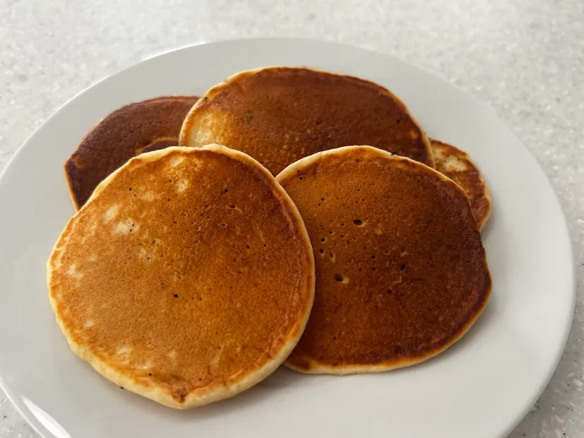 Stack of fluffy dairy-free pancakes on a white plate