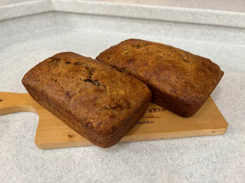 Two loaves of dairy-free banana bread on a wooden cutting board