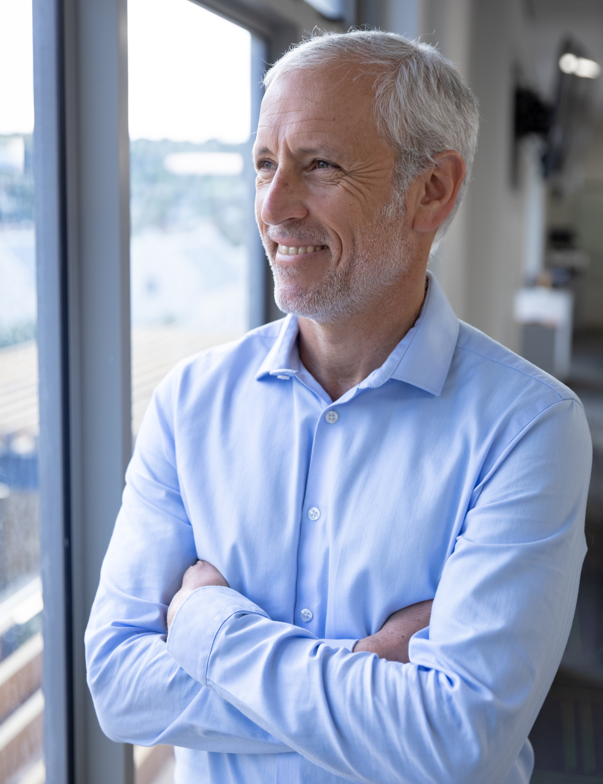 Happy mid-aged man in a blue shirt looking trough a window. 
